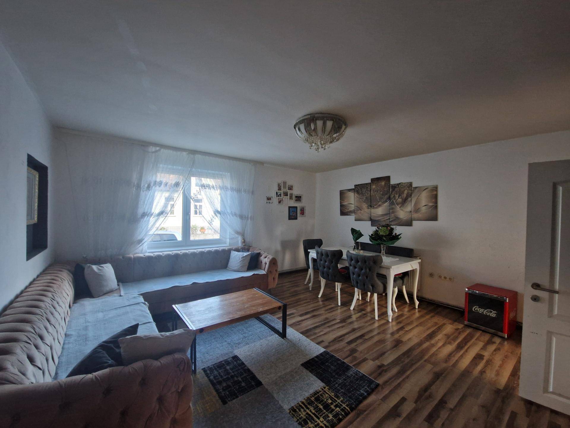 Geräumiger Wohn-Essbereich mit bequemer Couch, Esstisch und Laminatboden.