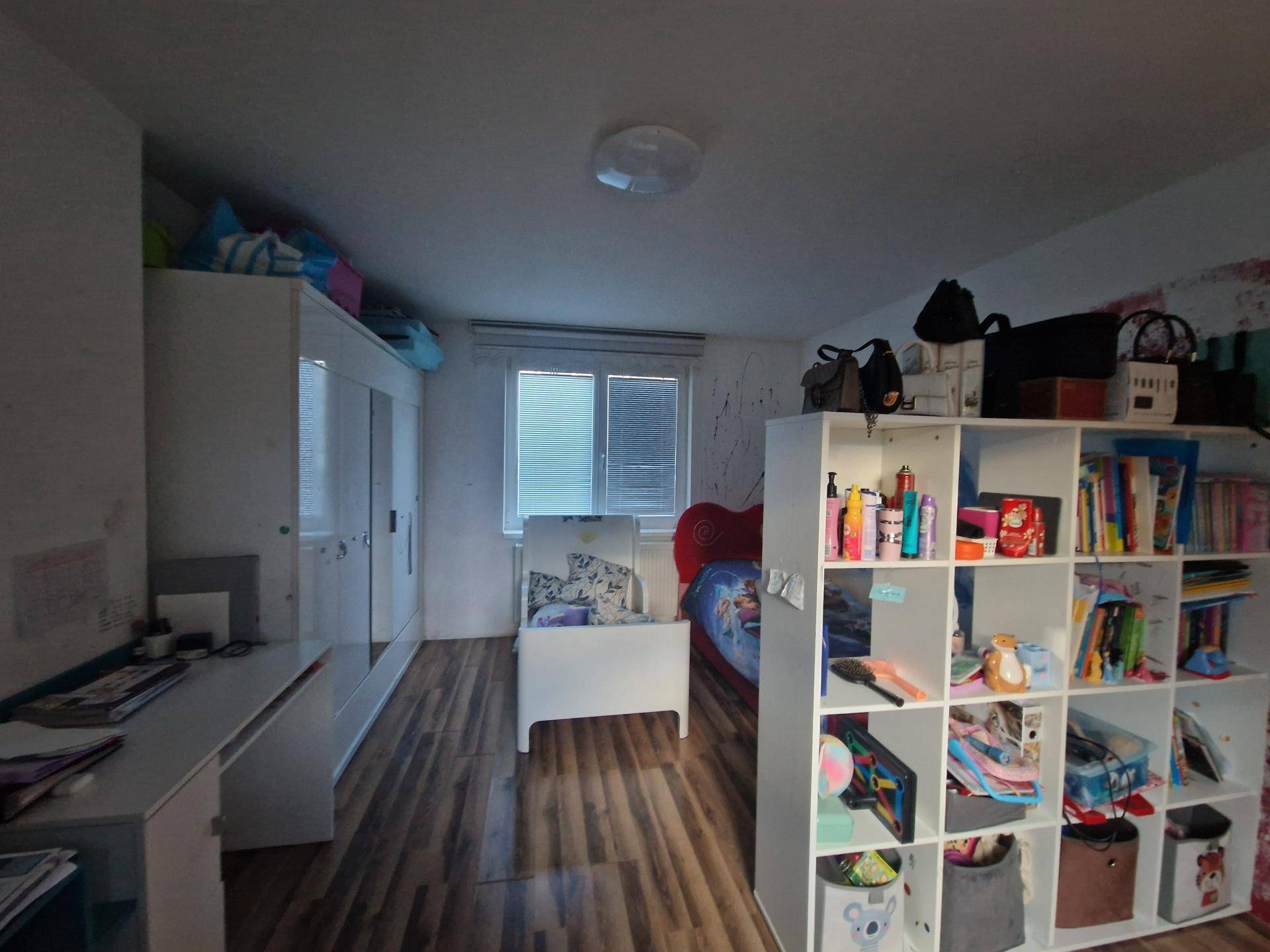 Helles Kinderzimmer mit weißen Möbeln, viel Stauraum und Laminatboden.