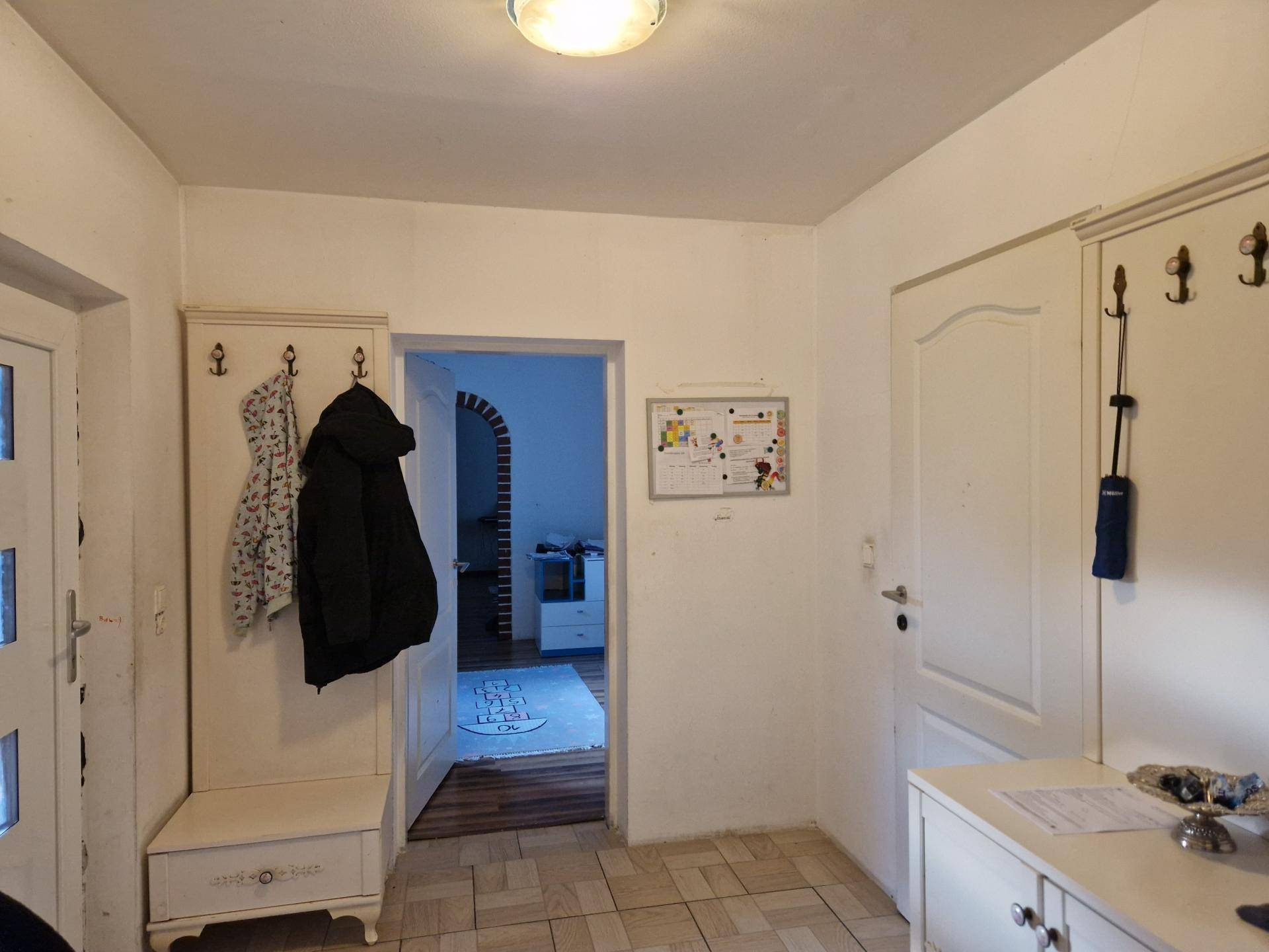 Heller Eingangsbereich mit Fliesenboden, Garderobe und Zugang zu weiteren Räumen.