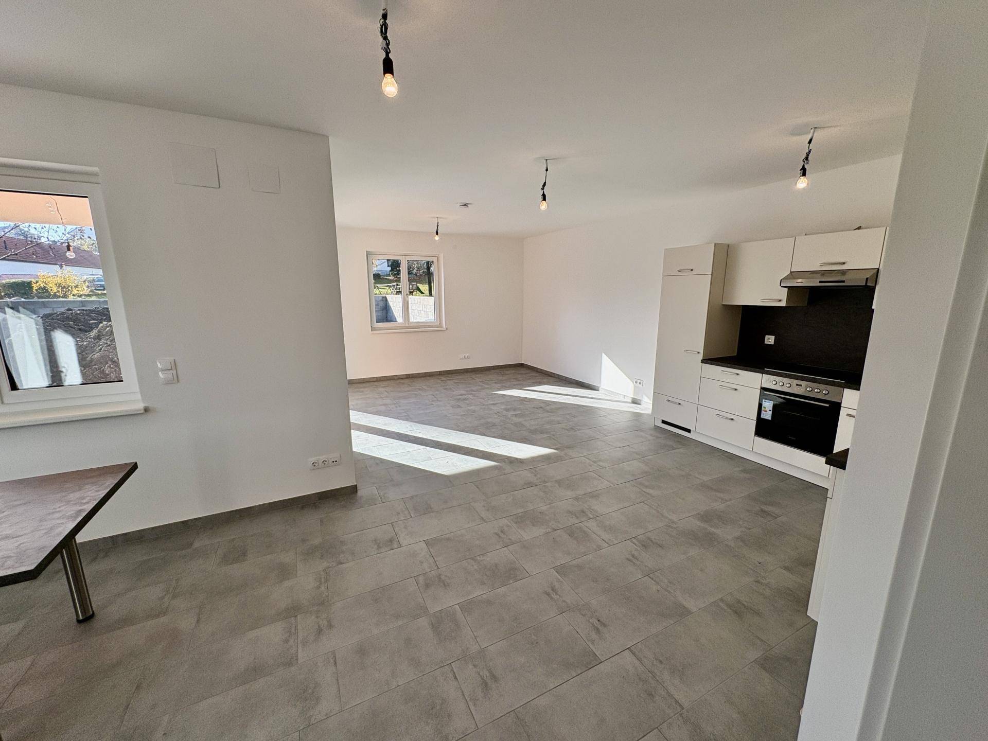 Geräumiger, lichtdurchfluteter Wohnbereich mit offener Küche und Blick ins Grüne.