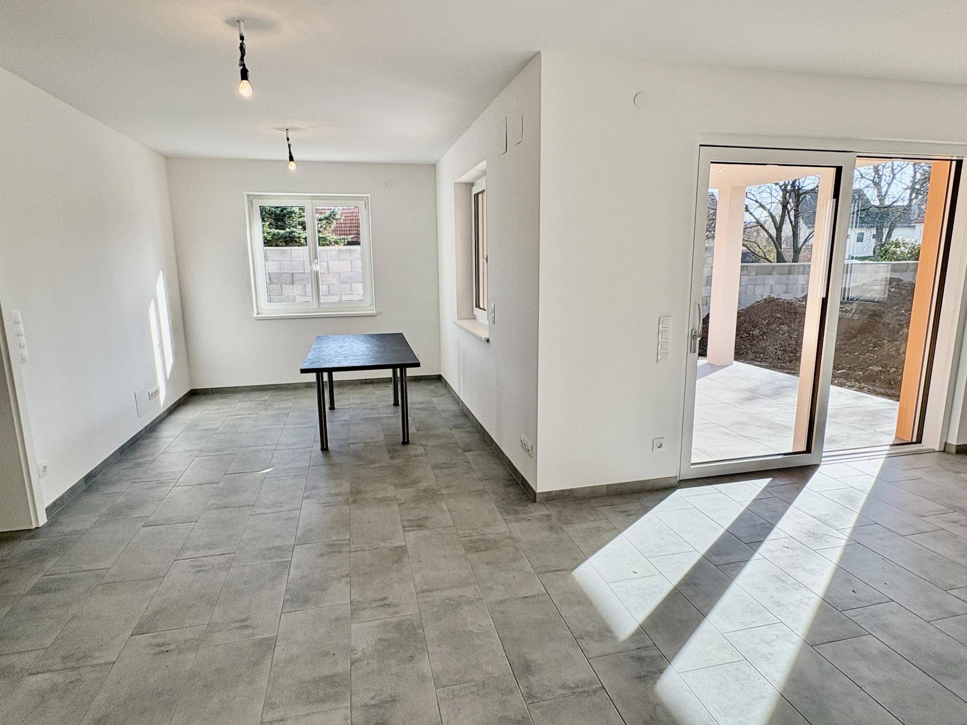 Heller Essbereich mit einem Tisch und Zugang zur Außenterrasse durch eine große Schiebetür.