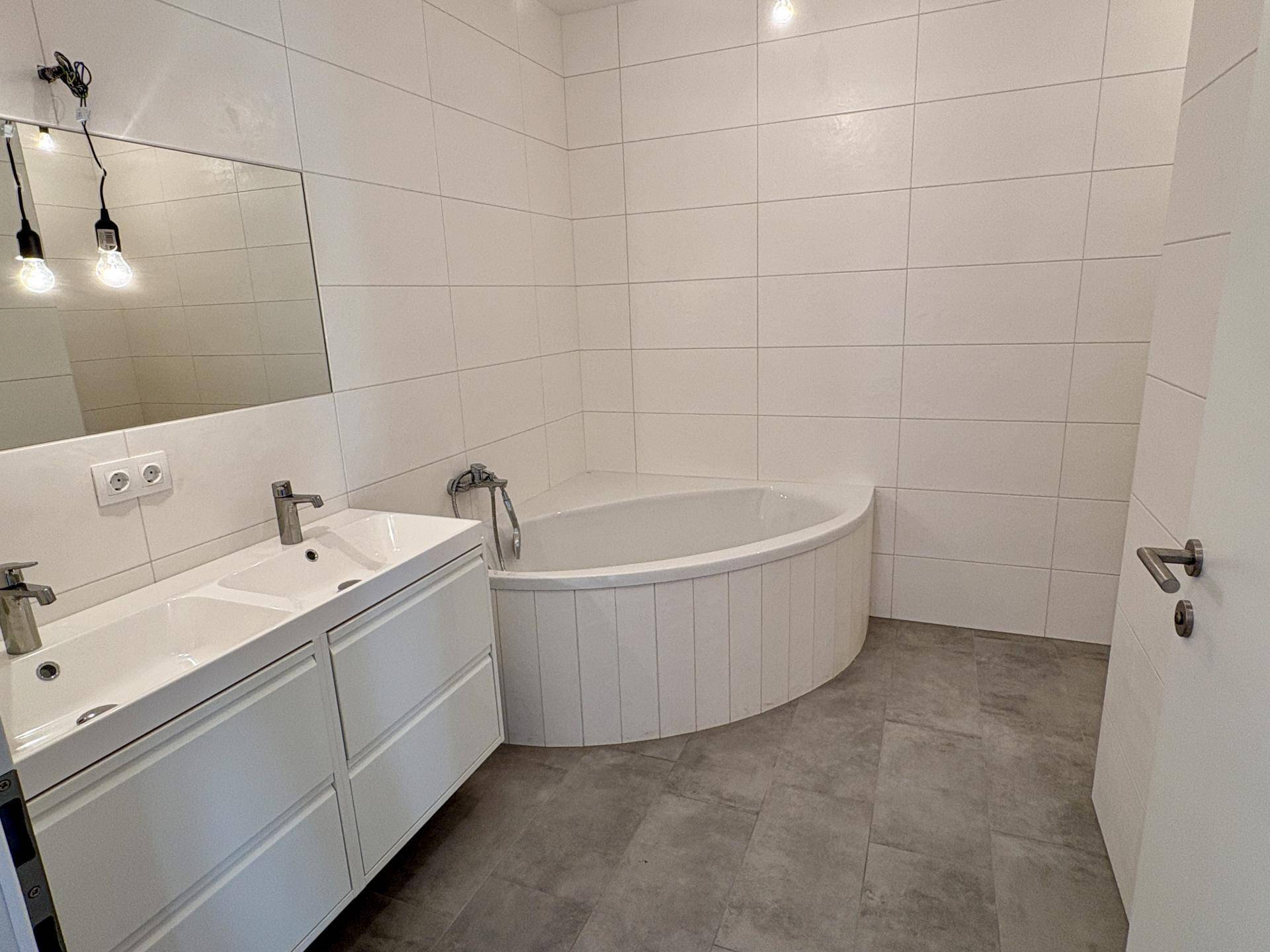 Modernes Badezimmer mit Doppelwaschbecken, großer Spiegelfläche und Eckbadewanne.