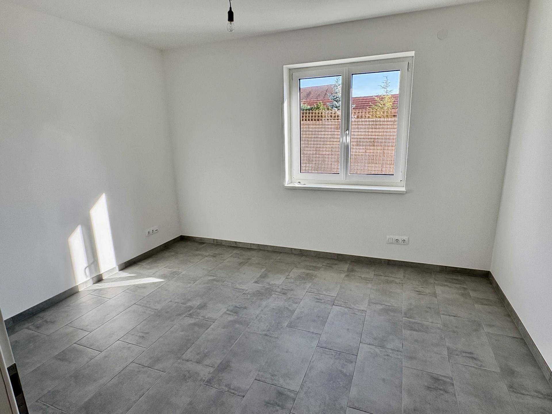 Helles Schlafzimmer mit großen Fenstern und modernen grauen Fliesenboden.