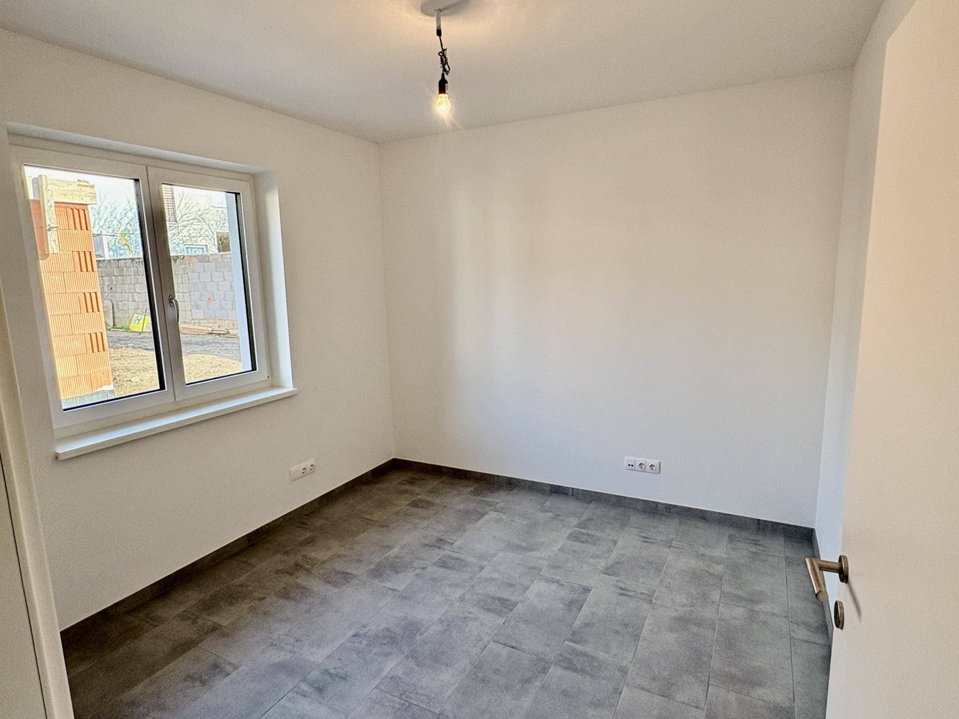 Geräumiges Schlafzimmer mit Fliesenboden und einem großen Fenster für natürliche Belichtung.