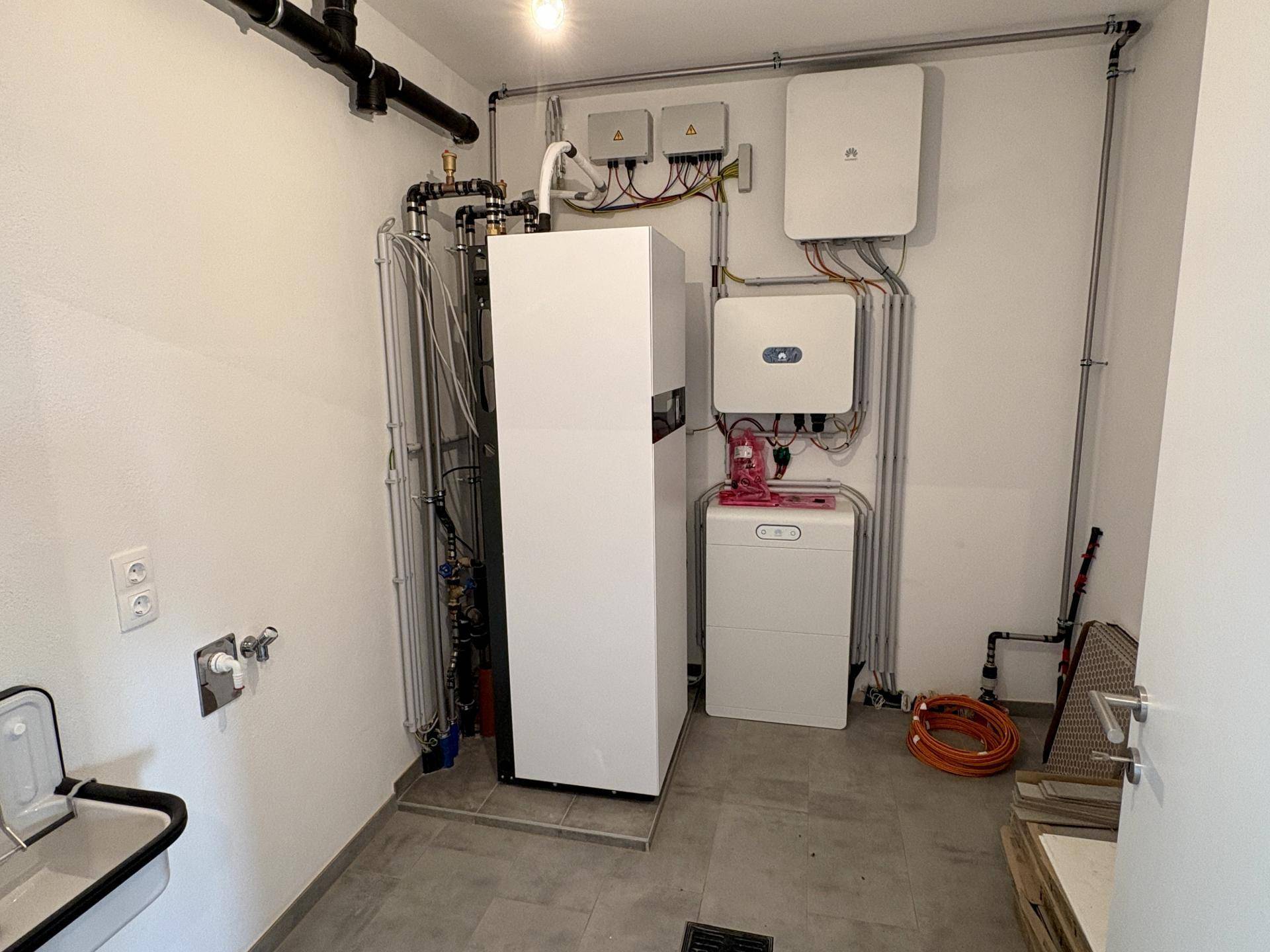 Technikraum mit Wärmepumpe, Photovoltaik-Wechselrichtern und Anschlüssen.
