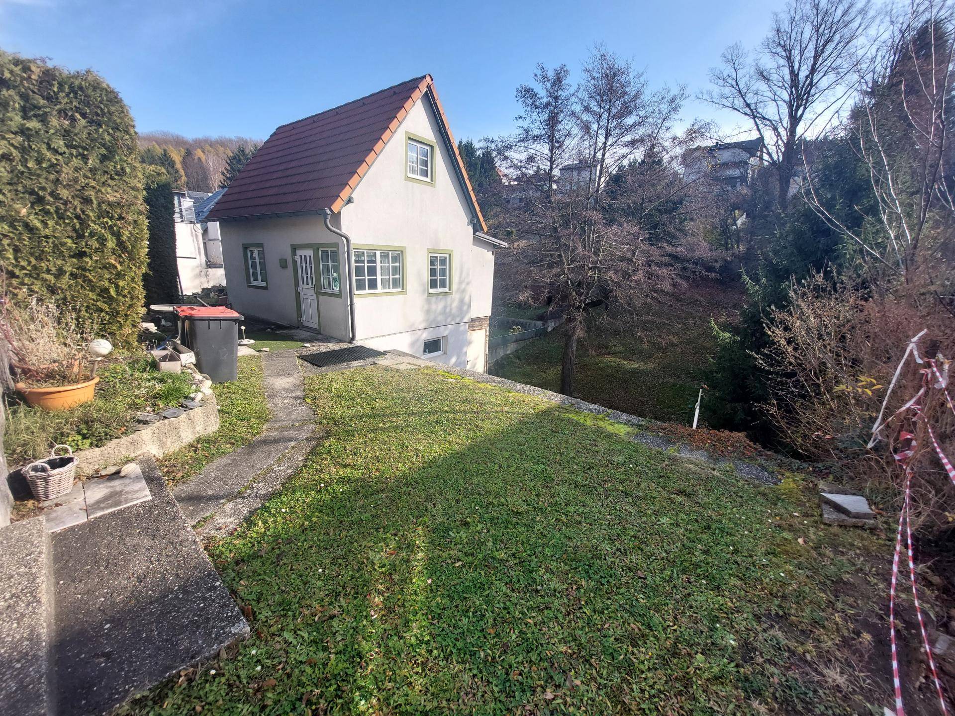 Einfamilienhaus mit Satteldach und großem Gartenbereich in sonniger Hanglage.