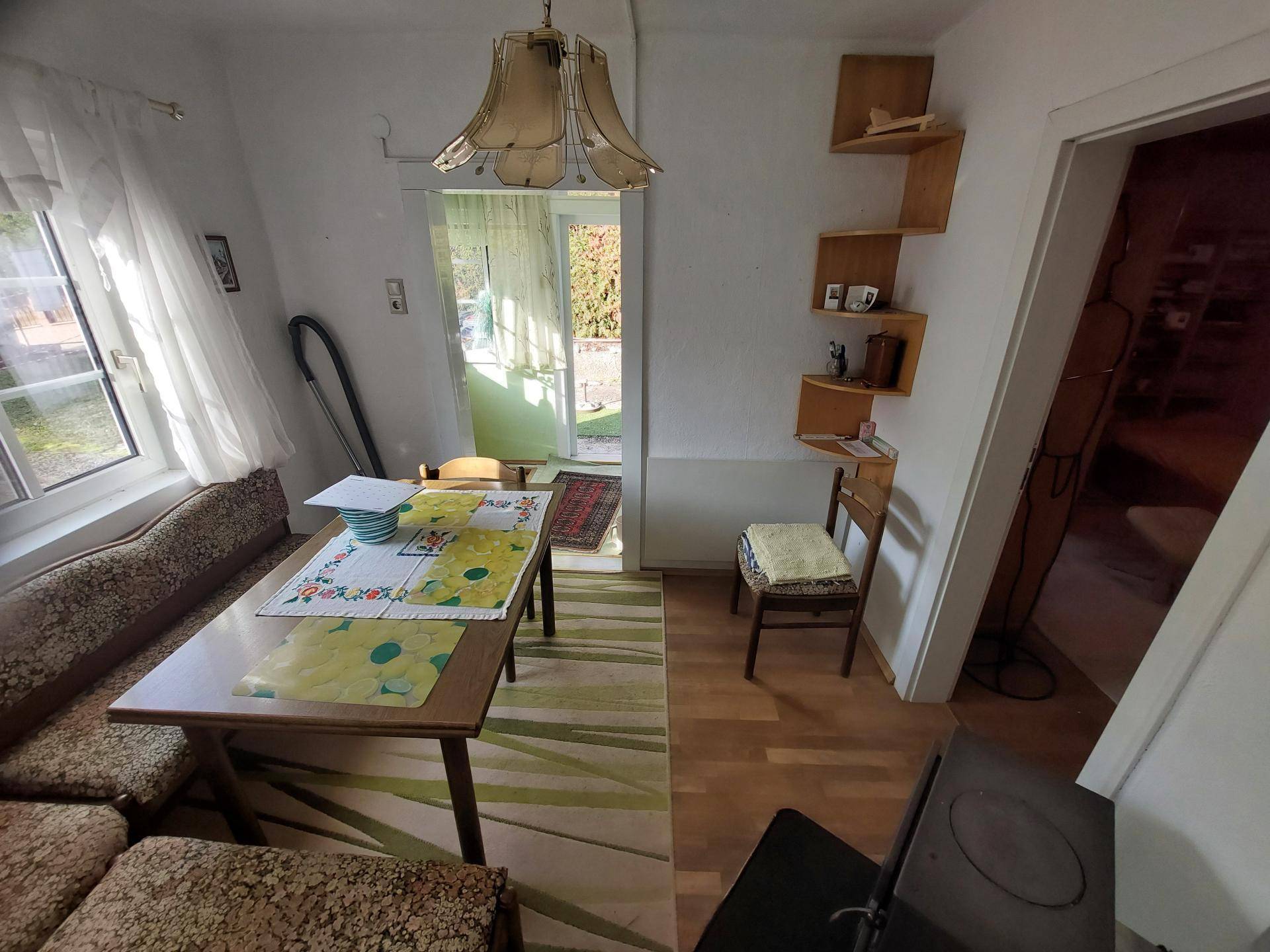 Heller Essbereich mit Holztisch, Eckbank und Zugang zum Außenbereich durch eine Tür.