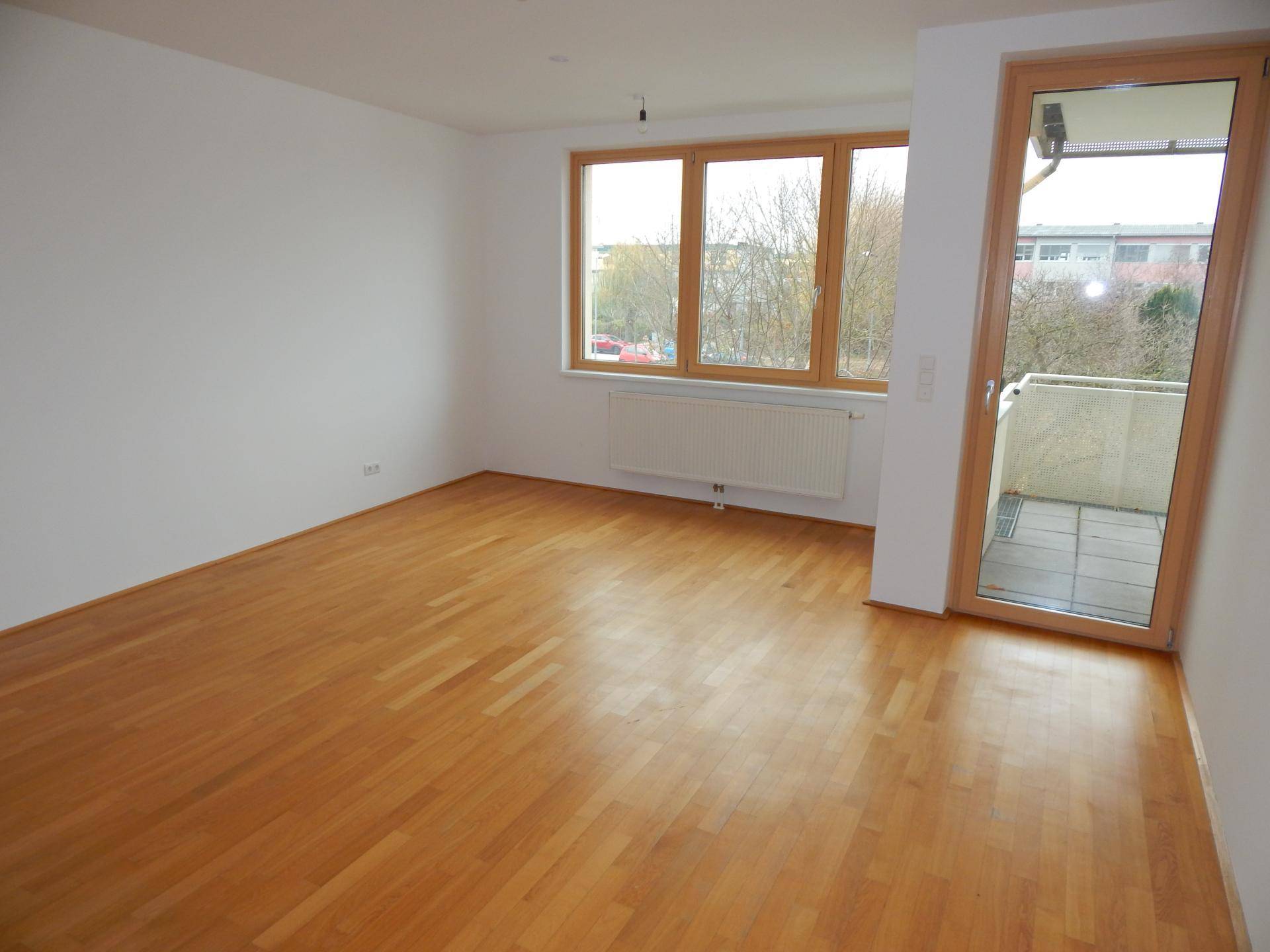 Geräumiges, helles Zimmer mit Parkettboden und direktem Zugang zu einem Außenbereich.