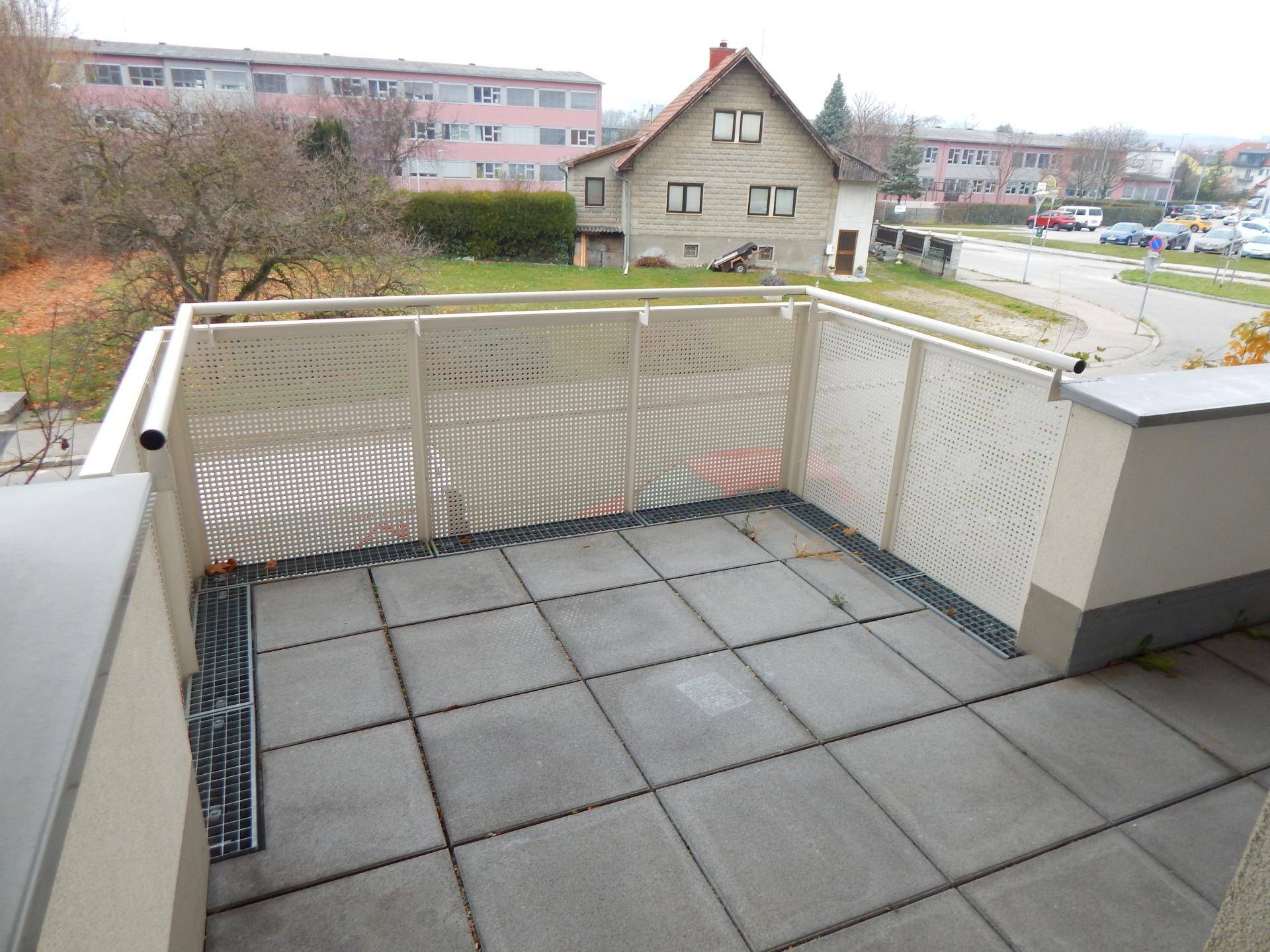 Geräumige, geflieste Terrasse mit Gitterzaun und Blick auf die Umgebung.
