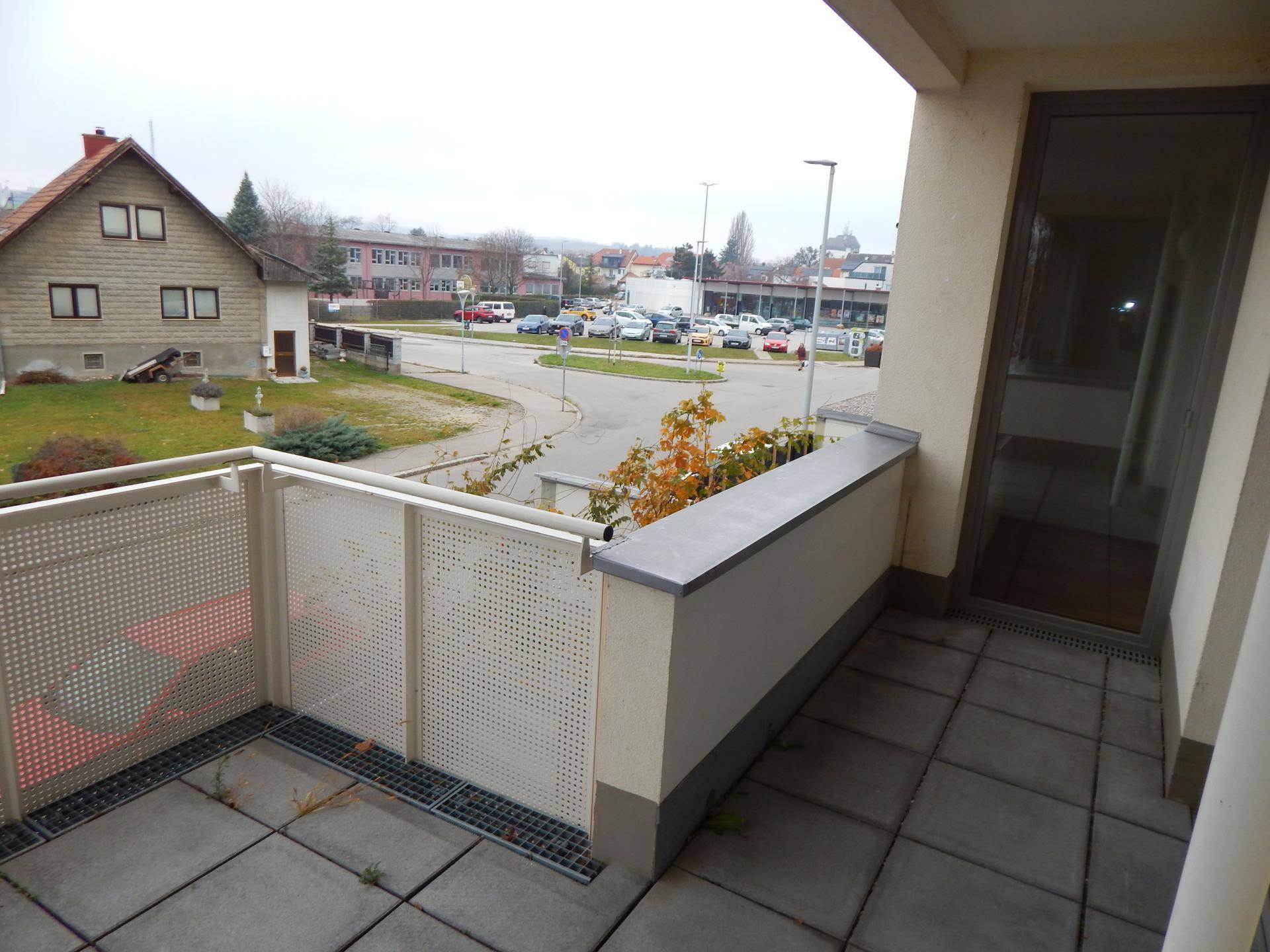 Terrasse mit Fliesenboden und Zugang zum Innenbereich, umgeben von einer Wohnsiedlung.