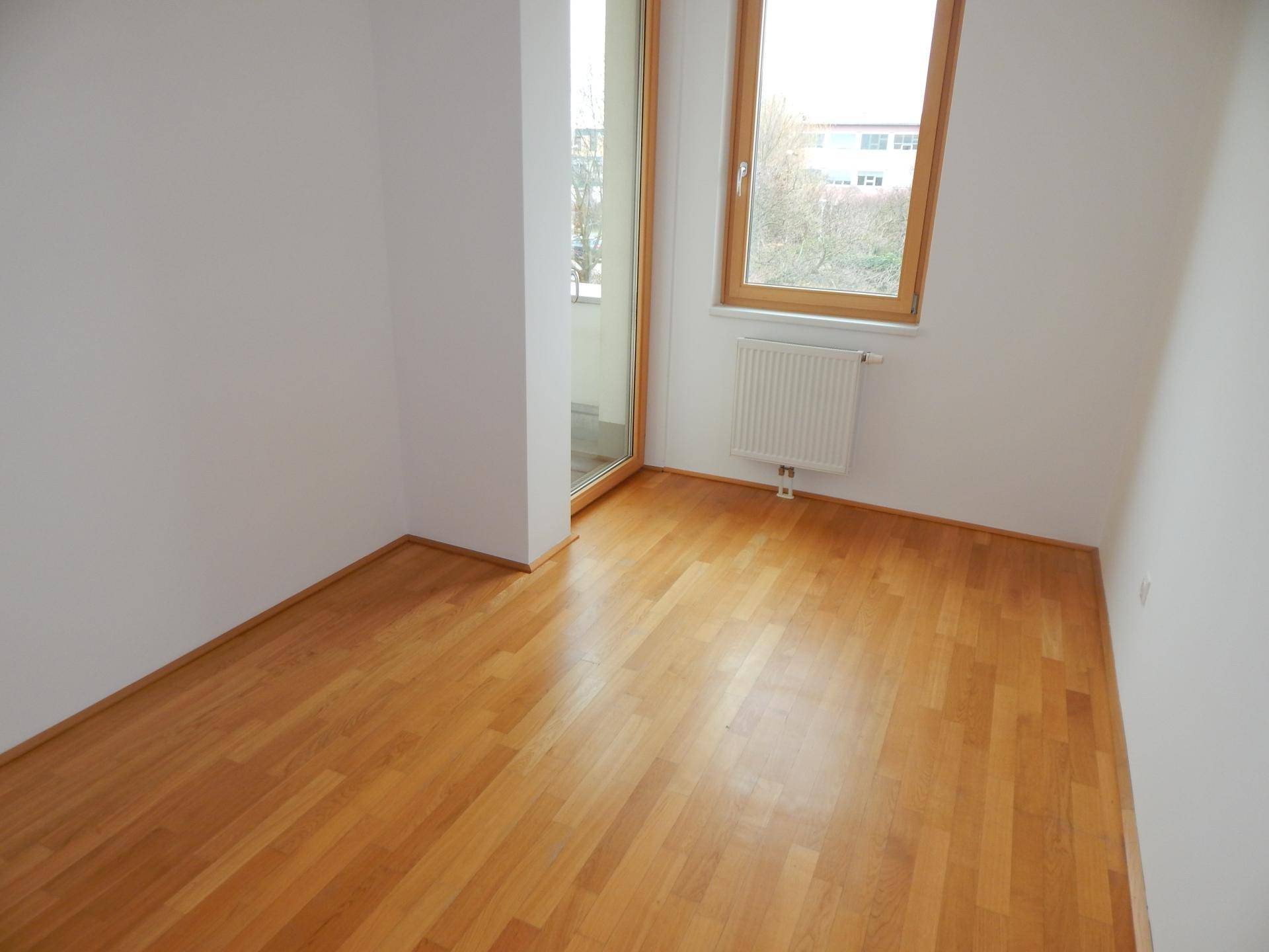 Helles Zimmer mit Holzboden und Fenster, ideal als Schlaf- oder Arbeitszimmer.