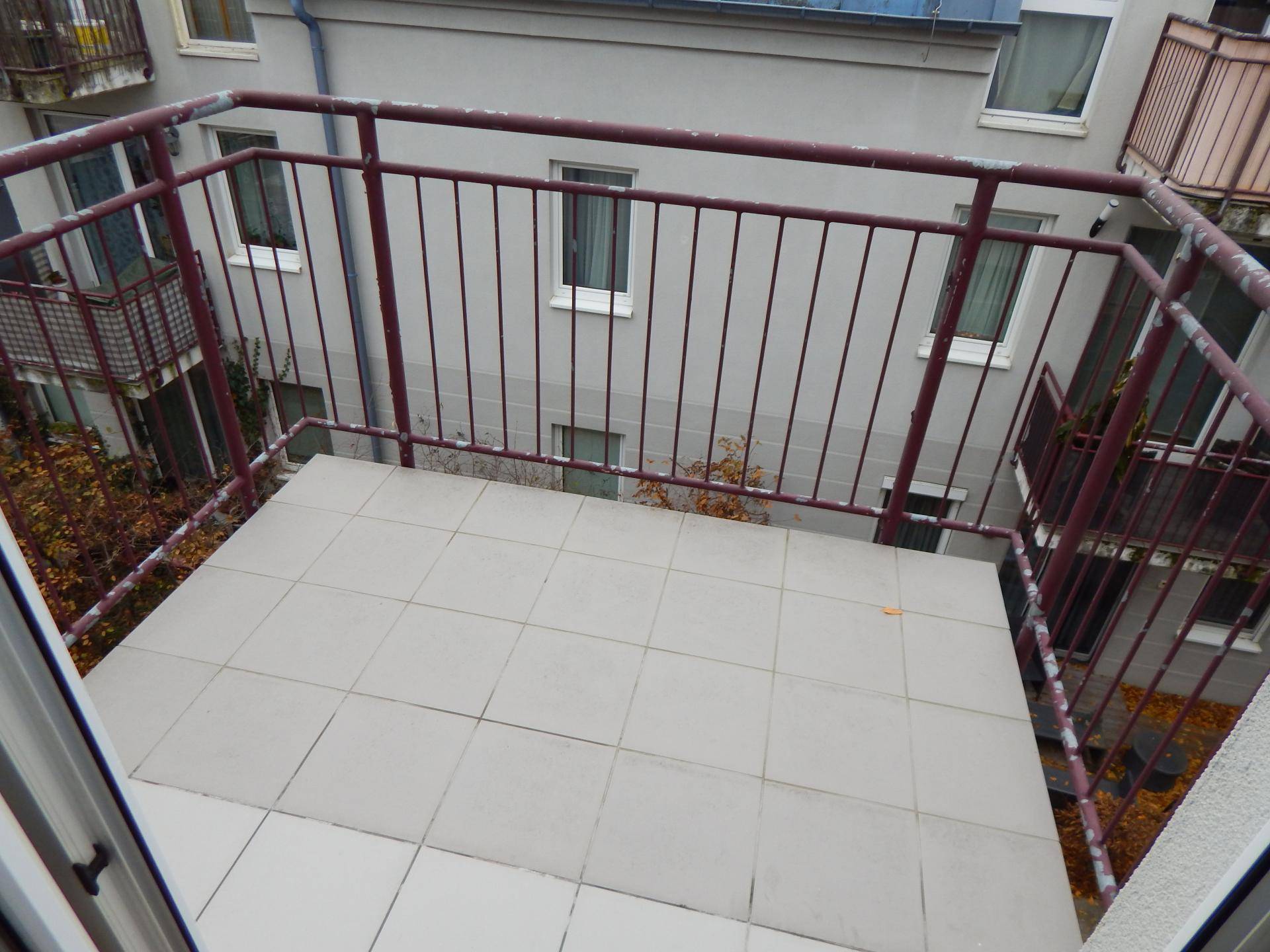 Kleiner Balkon mit Fliesenboden und Metallgeländer, bietet einen Blick auf den Innenhof.