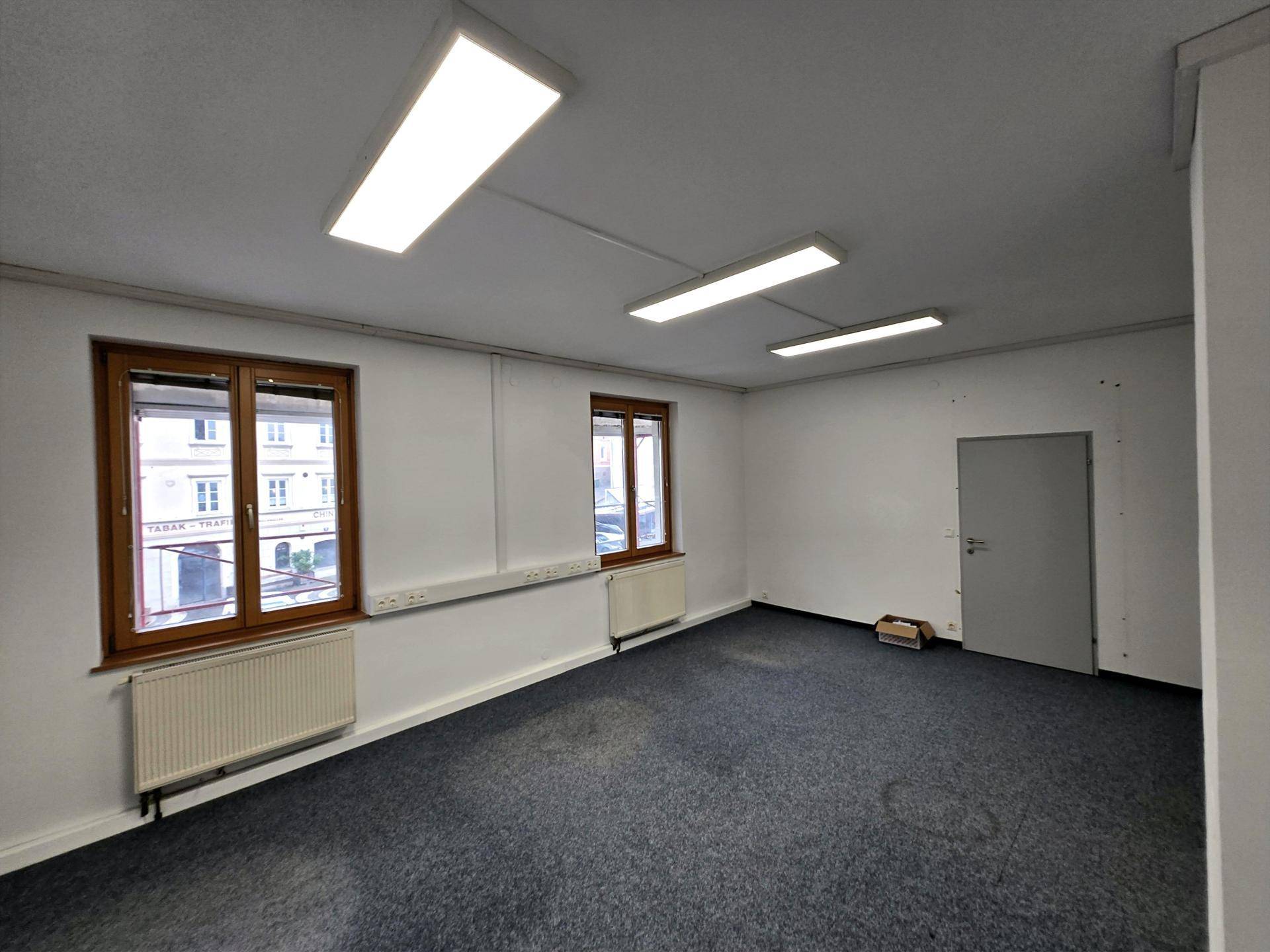 Geräumiger Büroraum mit Teppichboden, weißen Wänden und einer Tür, bereit zur individuellen Gestaltung.