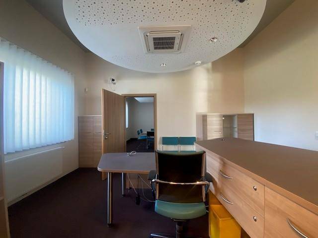 Modernes Büro mit Schreibtisch, Bürostuhl und Fenster, ausgestattet mit Teppichboden und Deckenklimaanlage.