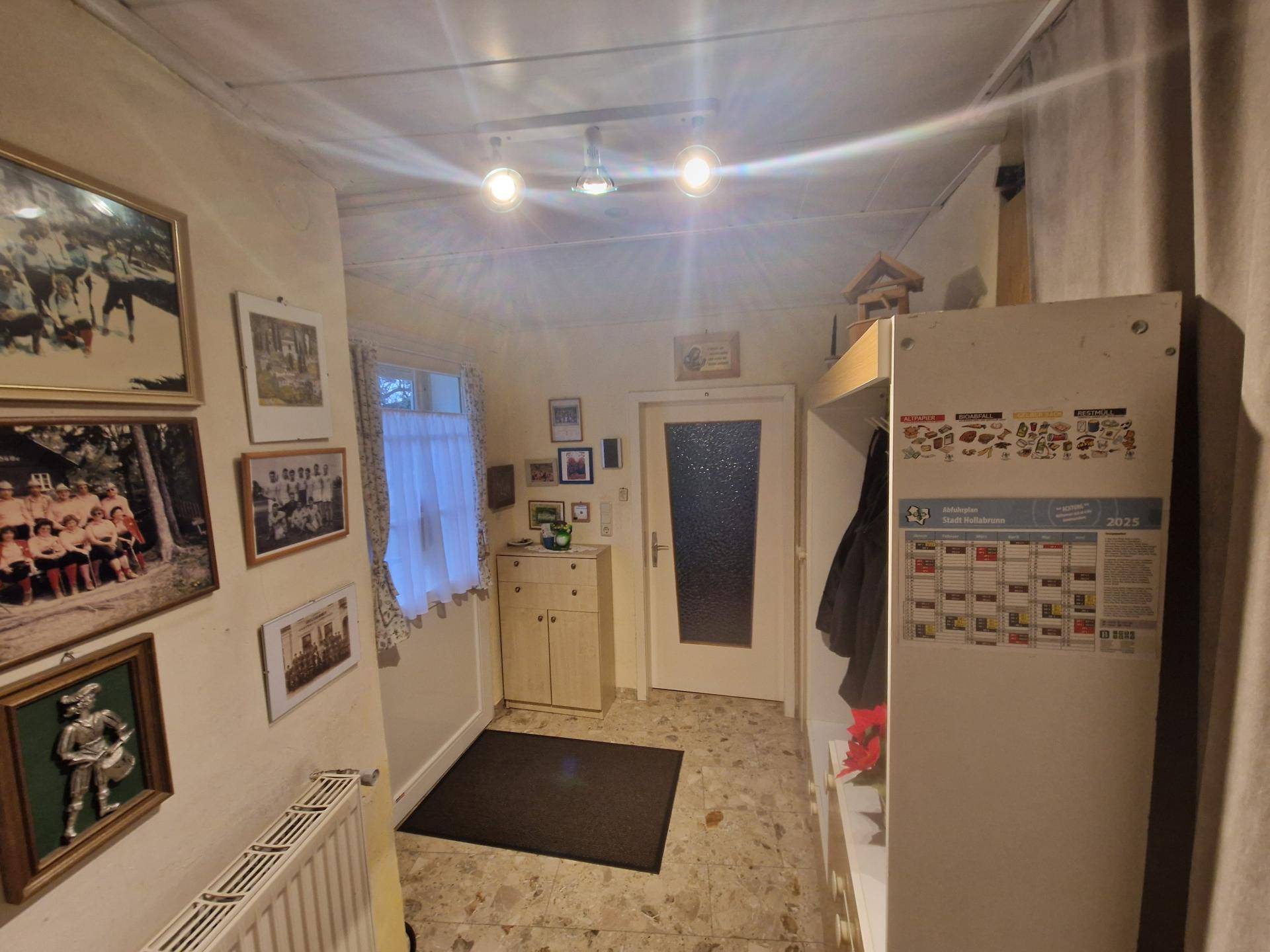 Eingangsbereich mit Garderobe, Schuhschrank und vielen Familienfotos an der Wand.