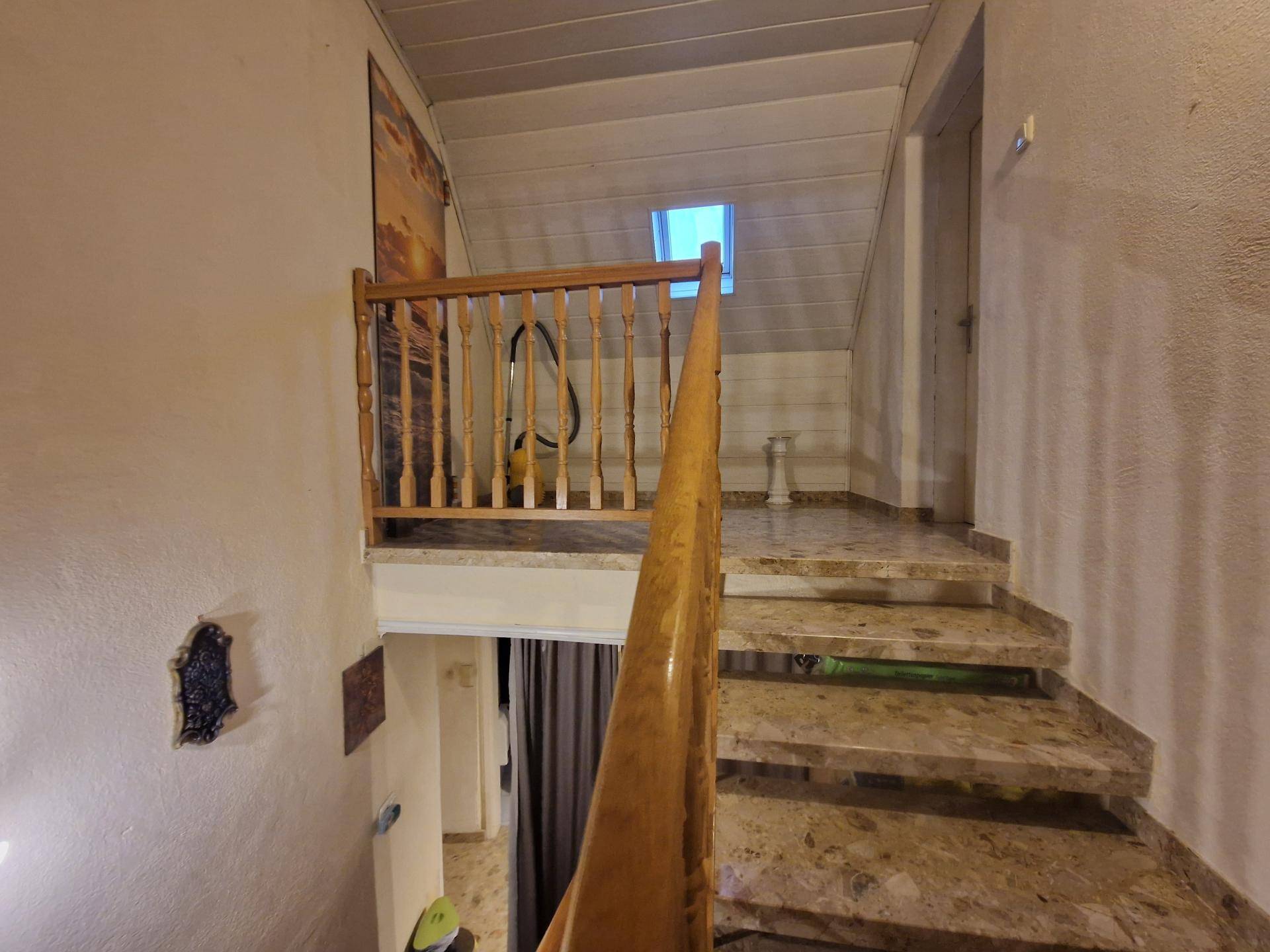 Treppenhaus mit Holzgeländer und Marmorstufen, das zu den oberen Etagen führt.