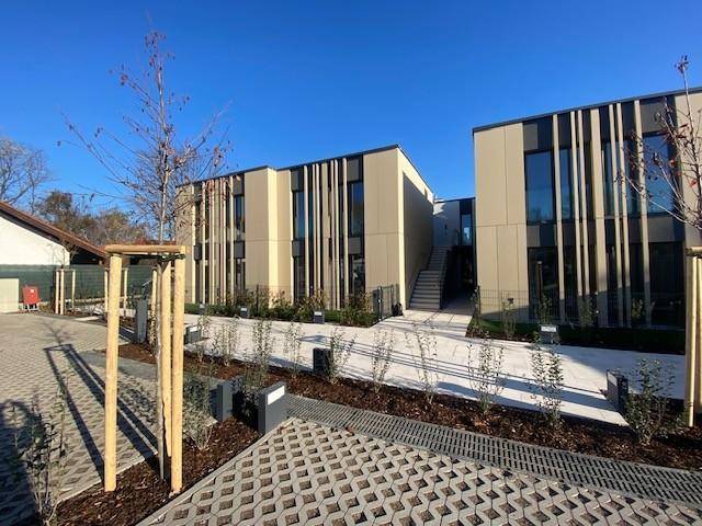 Zeitgenössische Wohngebäude mit vertikalen Fassadenakzenten und gepflastertem Eingangsbereich.