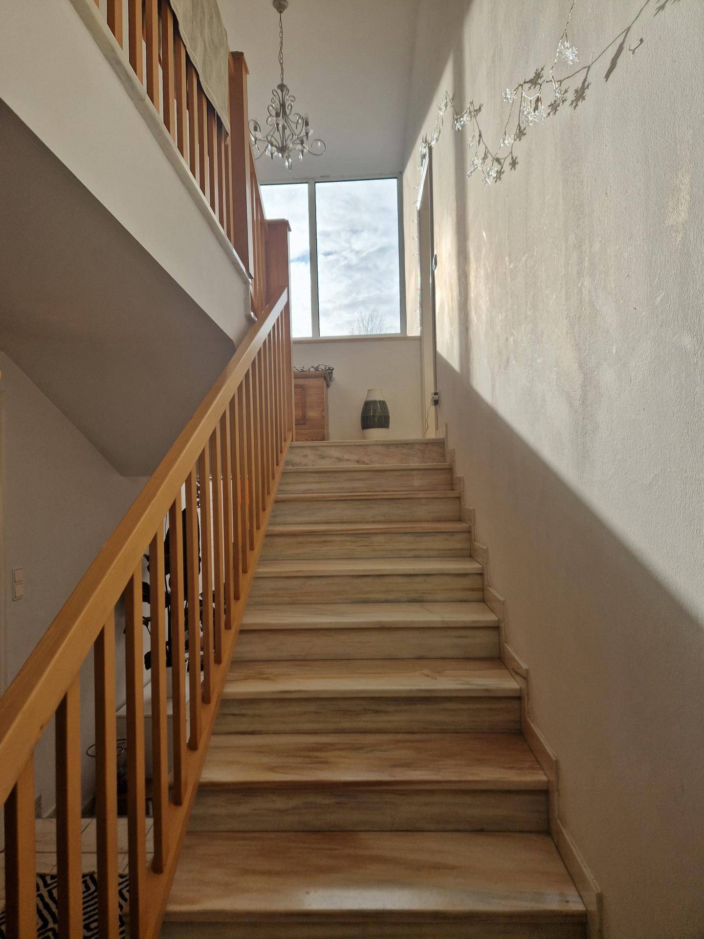 Treppenhaus mit Holzgeländer und marmorierten Stufen, das zu den oberen Etagen führt.