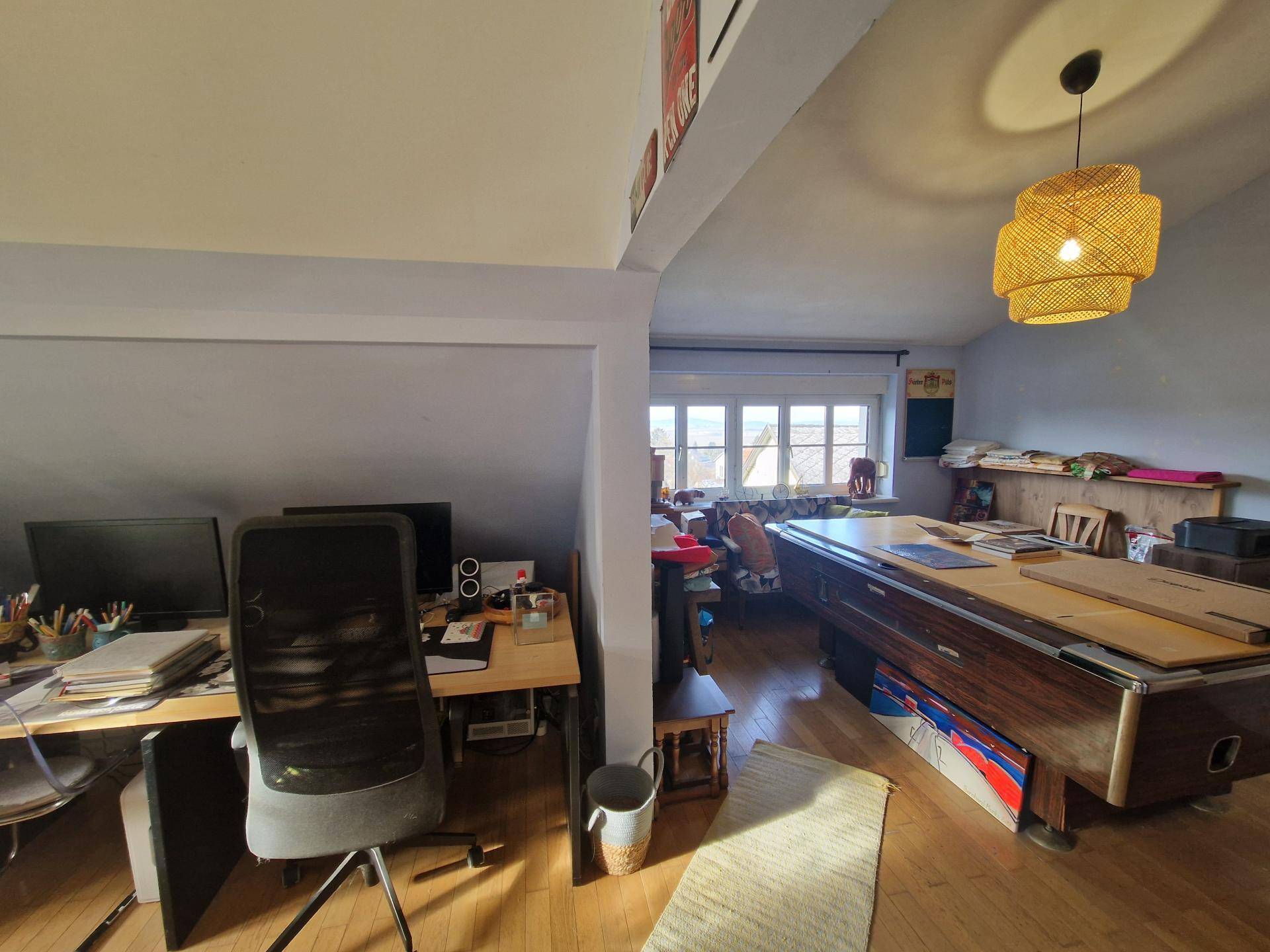 Geräumiges Arbeitszimmer mit Schreibtischen, Billardtisch und Dachschrägenfenstern.