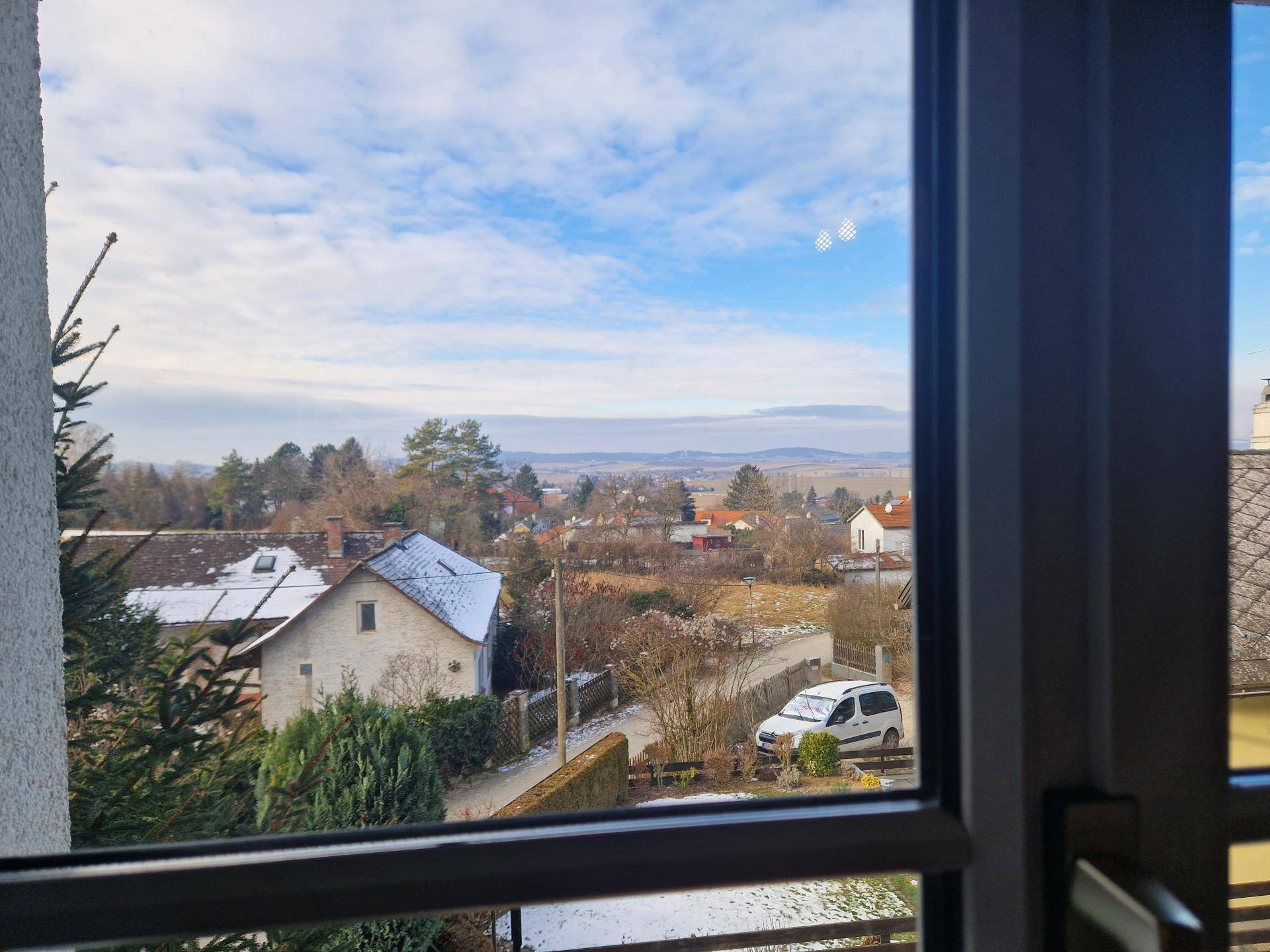 Weitläufiger Blick aus dem Fenster über die verschneite Landschaft und umliegende Häuser.