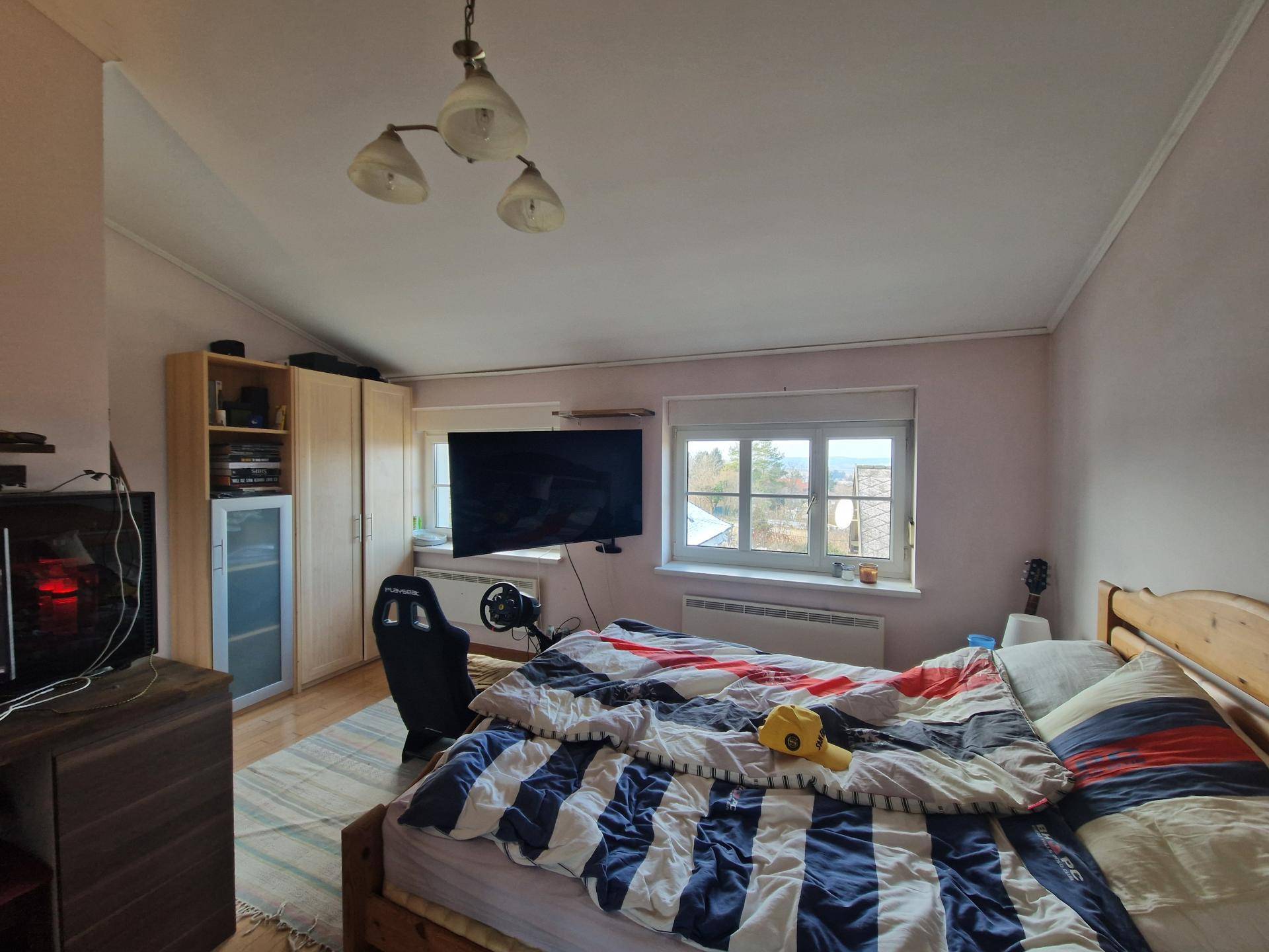 Schlafzimmer mit Holzboden, großem Fernseher und Blick auf die umliegende Landschaft.