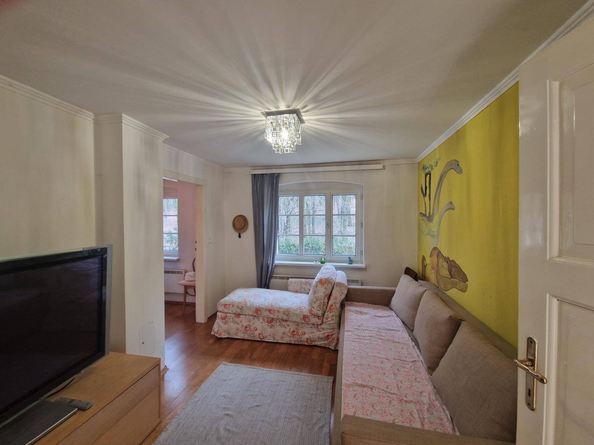 Helles Wohnzimmer mit Holzboden, bequemer Couch und gelber Akzentwand.