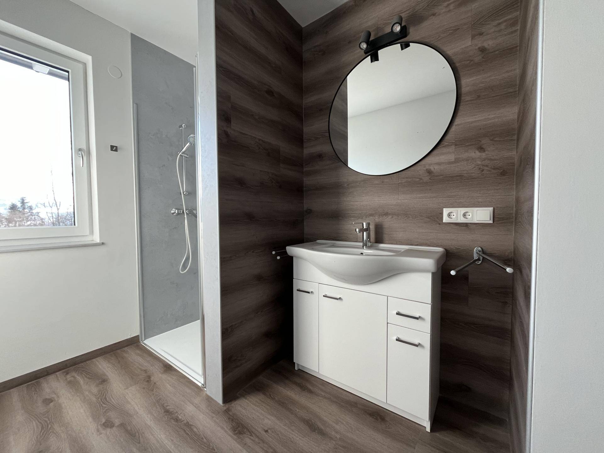 Modernes Badezimmer mit Waschtisch, Spiegel und begehbarer Dusche, hell und funktional.