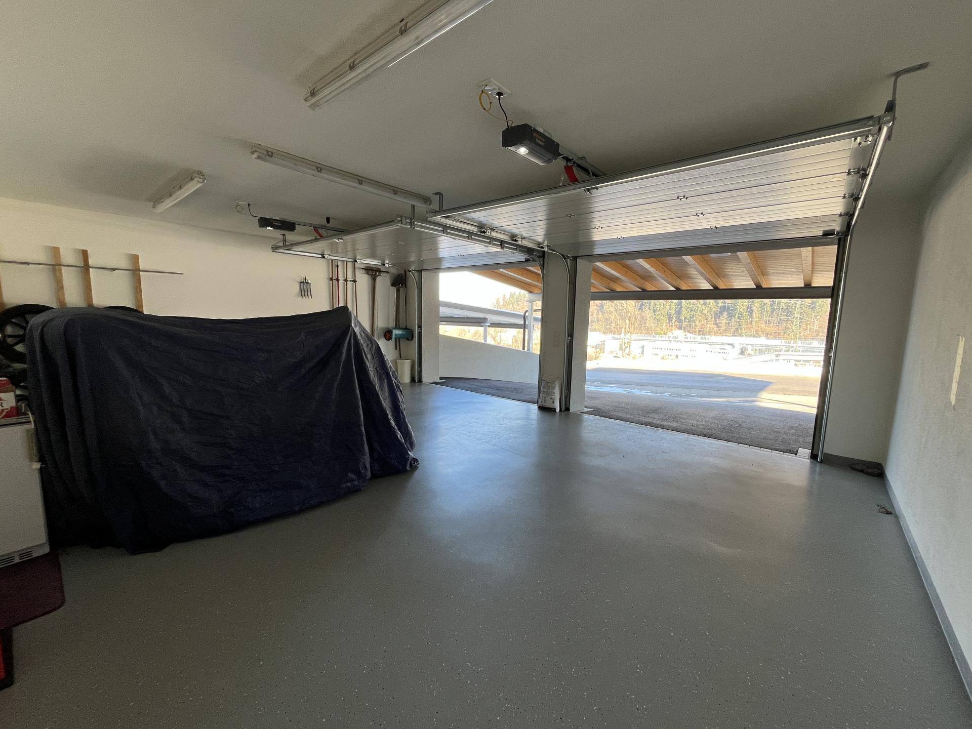 Geräumige Doppelgarage mit geöffneten Toren und Blick auf die verschneite Auffahrt.
