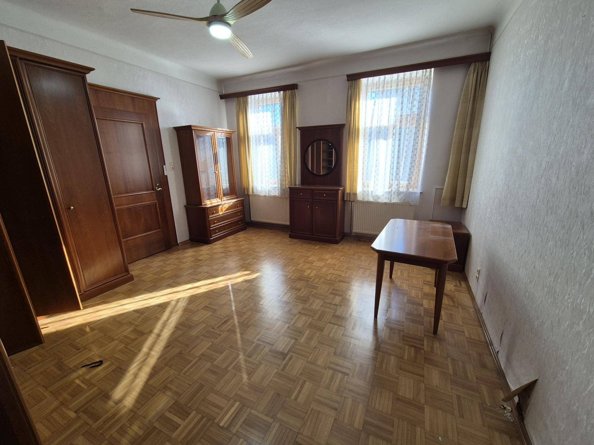 Geräumiges Schlafzimmer mit Parkettboden, Holzmöbeln und einem Deckenventilator.