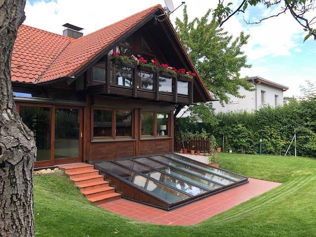 Ansicht des Hauses von der Gartenseite mit Poolzugang und Balkon mit Blumenkästen.