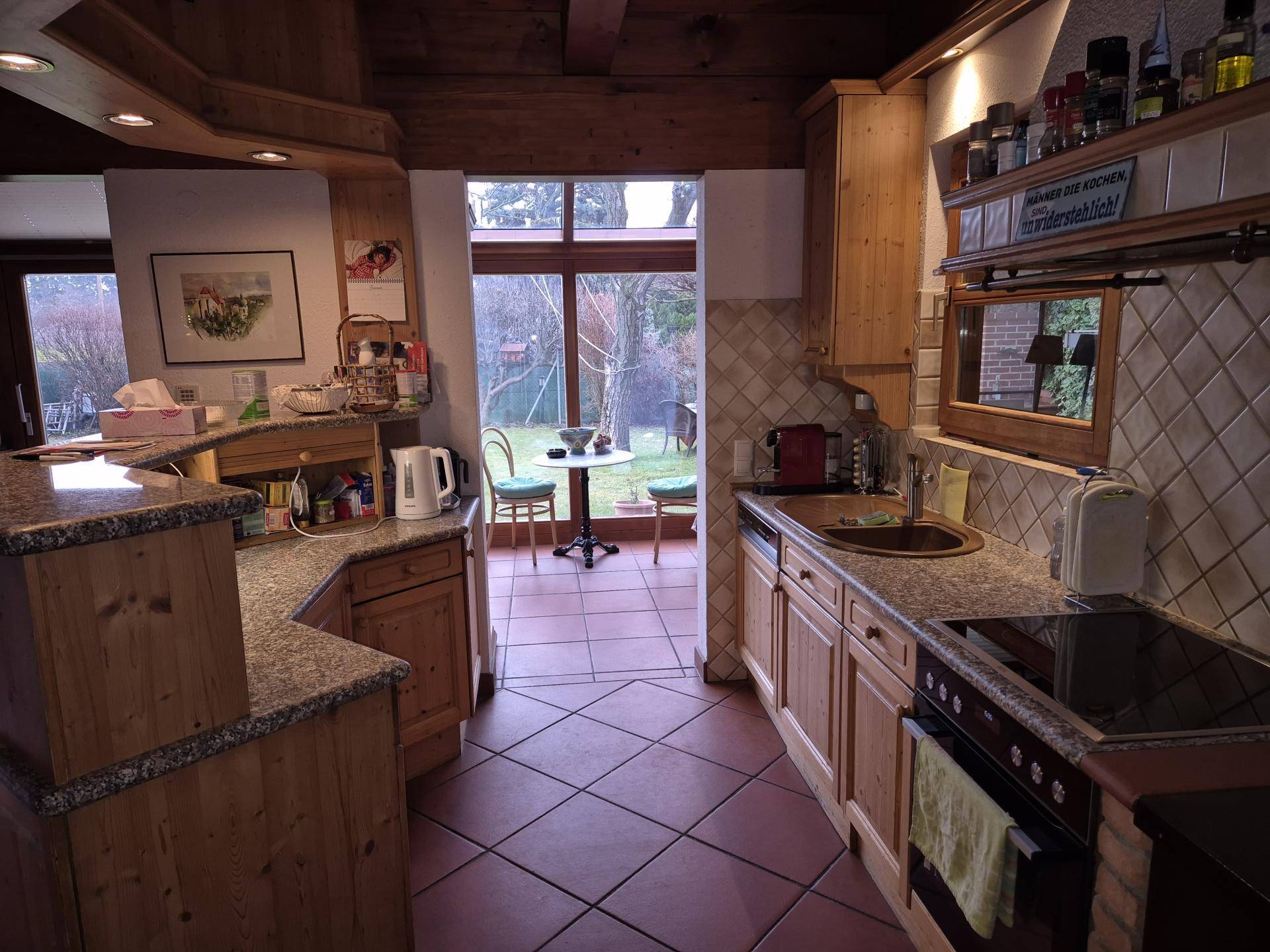 Rustikale Küche mit Holzschränken, Granitarbeitsplatten und Blick in den Garten.