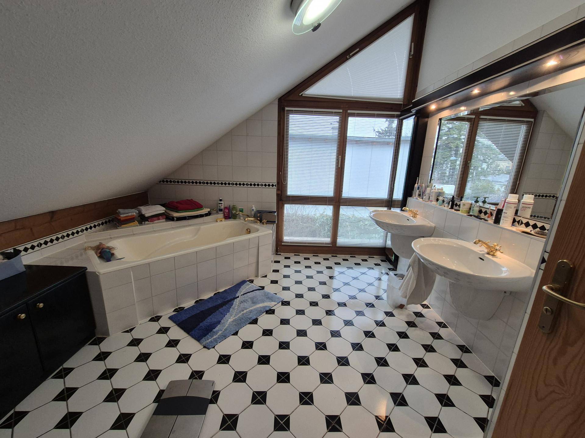 Geräumiges Badezimmer im Dachgeschoss mit Doppelwaschbecken, Badewanne und geometrischen Fliesen.