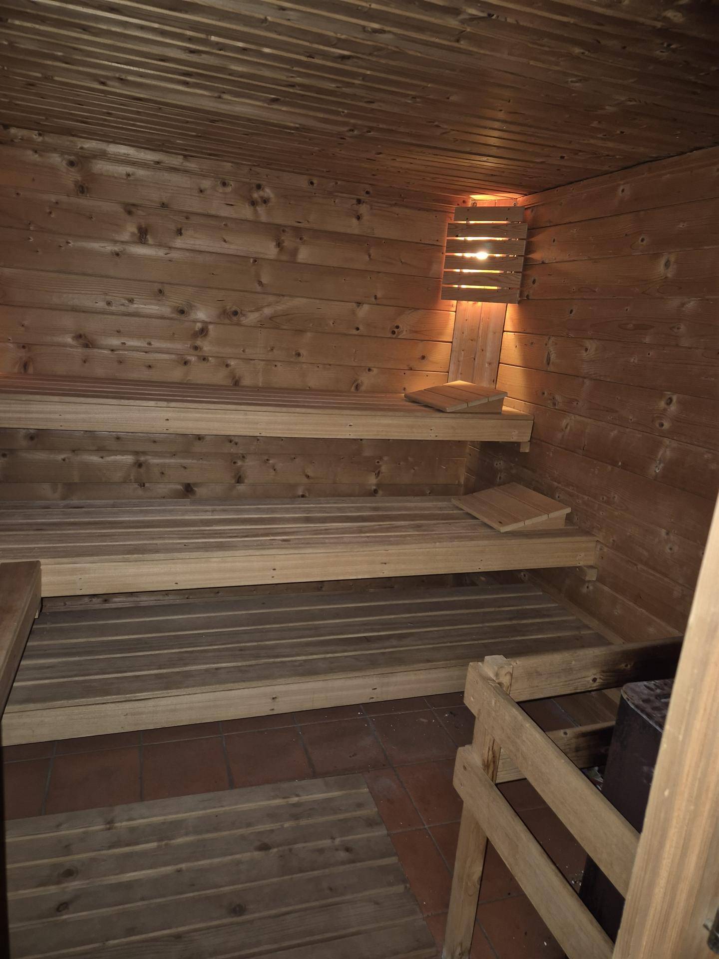 Traditionelle Holzsauna mit mehreren Bänken und stimmungsvoller Beleuchtung.
