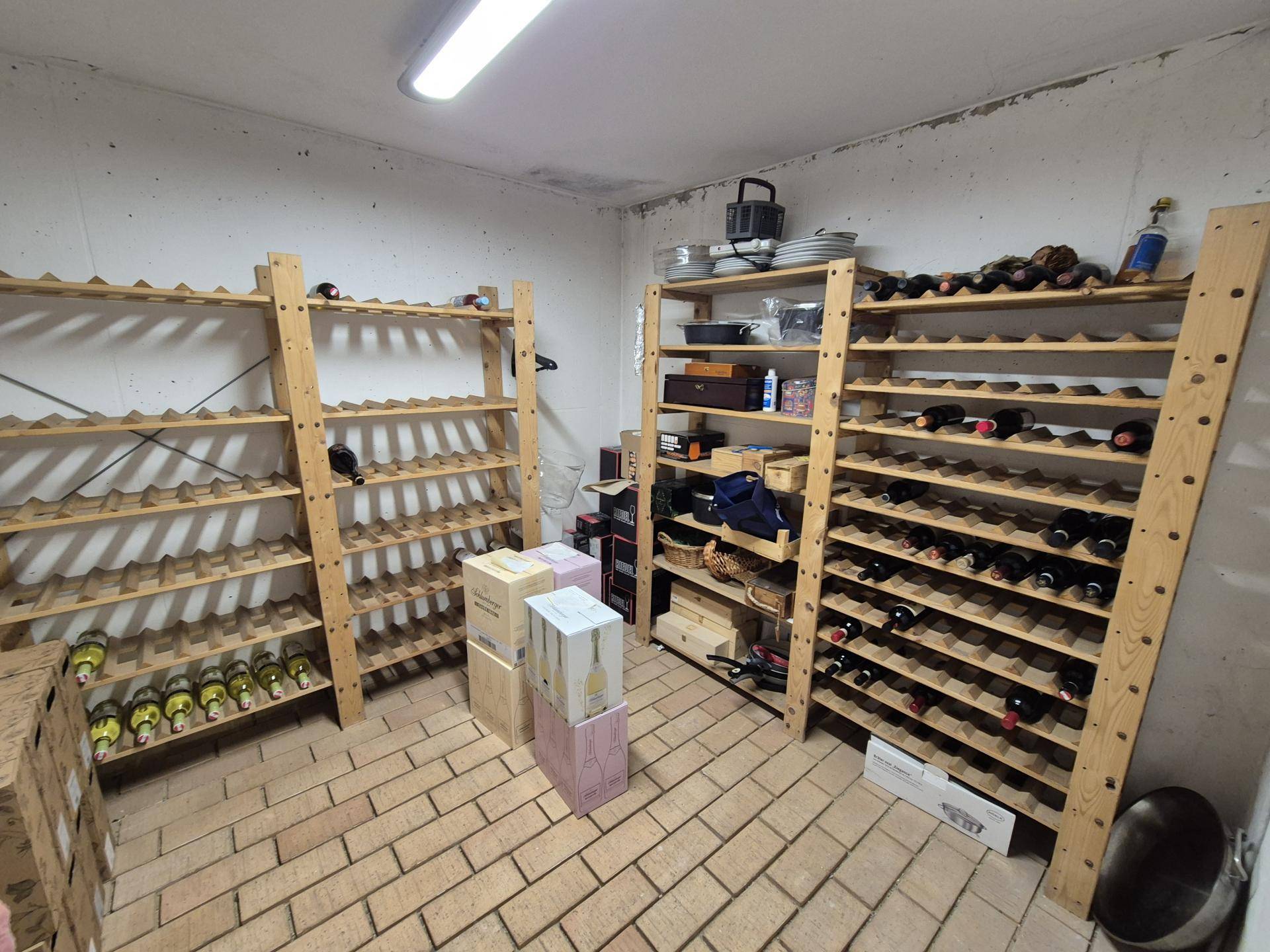 Weinkeller mit Holzregalen für Flaschenlagerung und Ziegelboden.