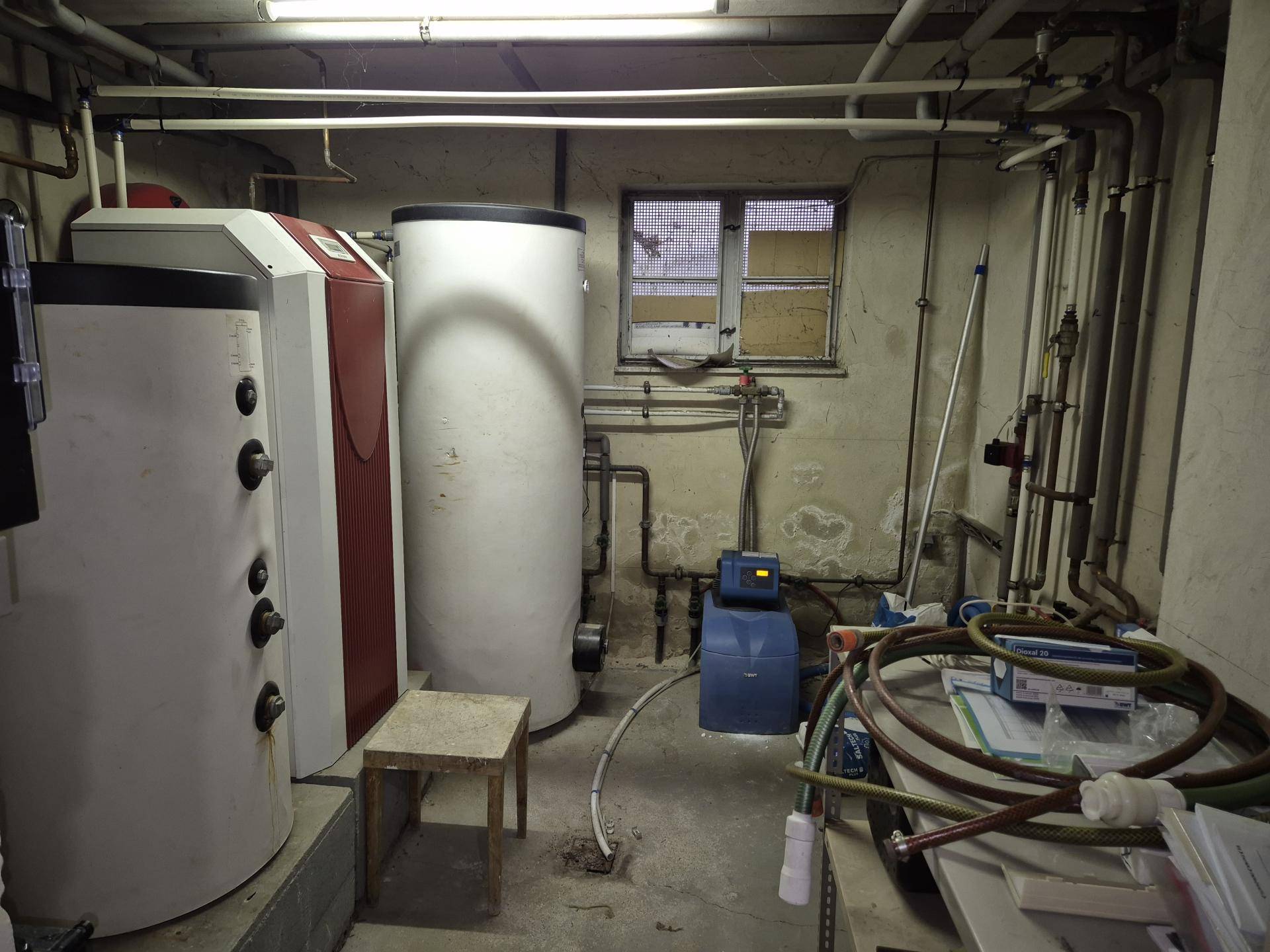 Heizungsraum im Keller mit Warmwasserspeichern und sichtbaren Rohren.