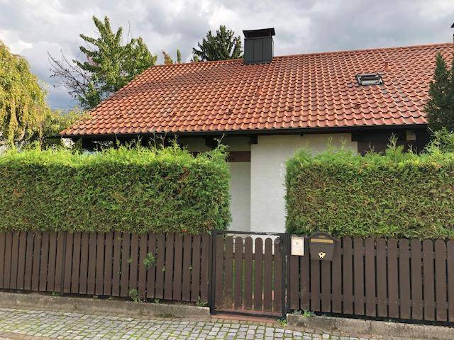 Vorderansicht des Hauses mit Satteldach, Holzzaun und gepflegter Hecke.