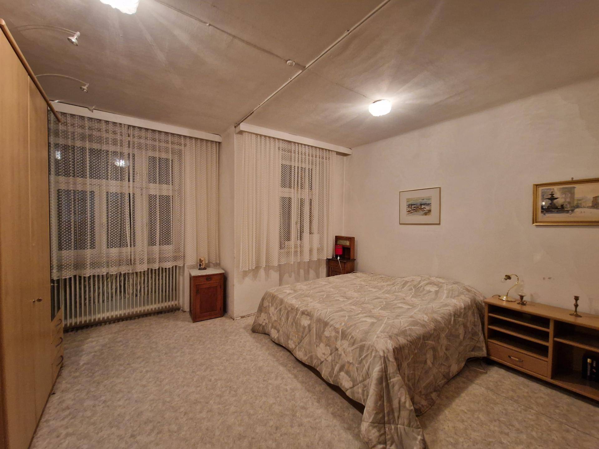 Schlafzimmer mit Teppichboden, Doppelbett und Einbauschrank, hell durch zwei Fenster.