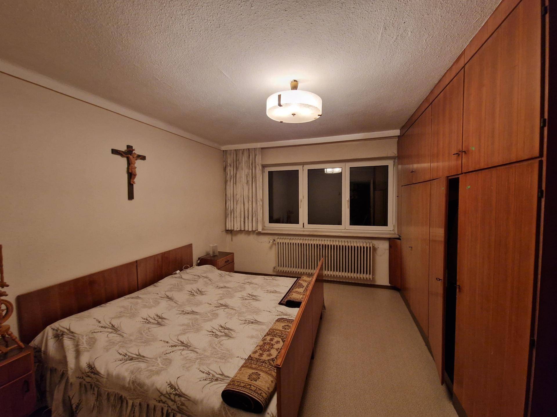 Schlafzimmer mit großem Einbauschrank, Doppelbett und Teppichboden, gut beleuchtet.