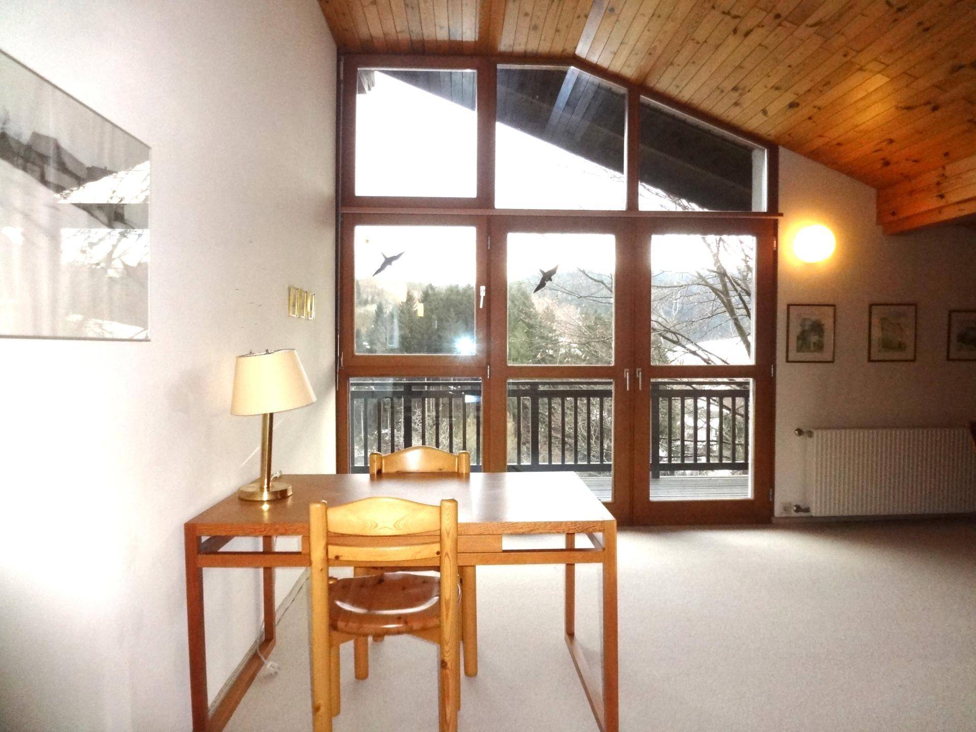 Arbeitsbereich im Dachgeschoss mit Holzdecke, großen Fenstern und weitem Ausblick.