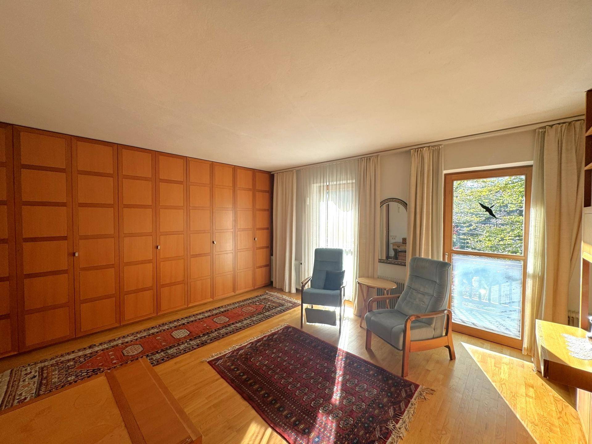 Helles Schlafzimmer mit eingebauten Holzschränken, Parkettboden und viel Tageslicht.