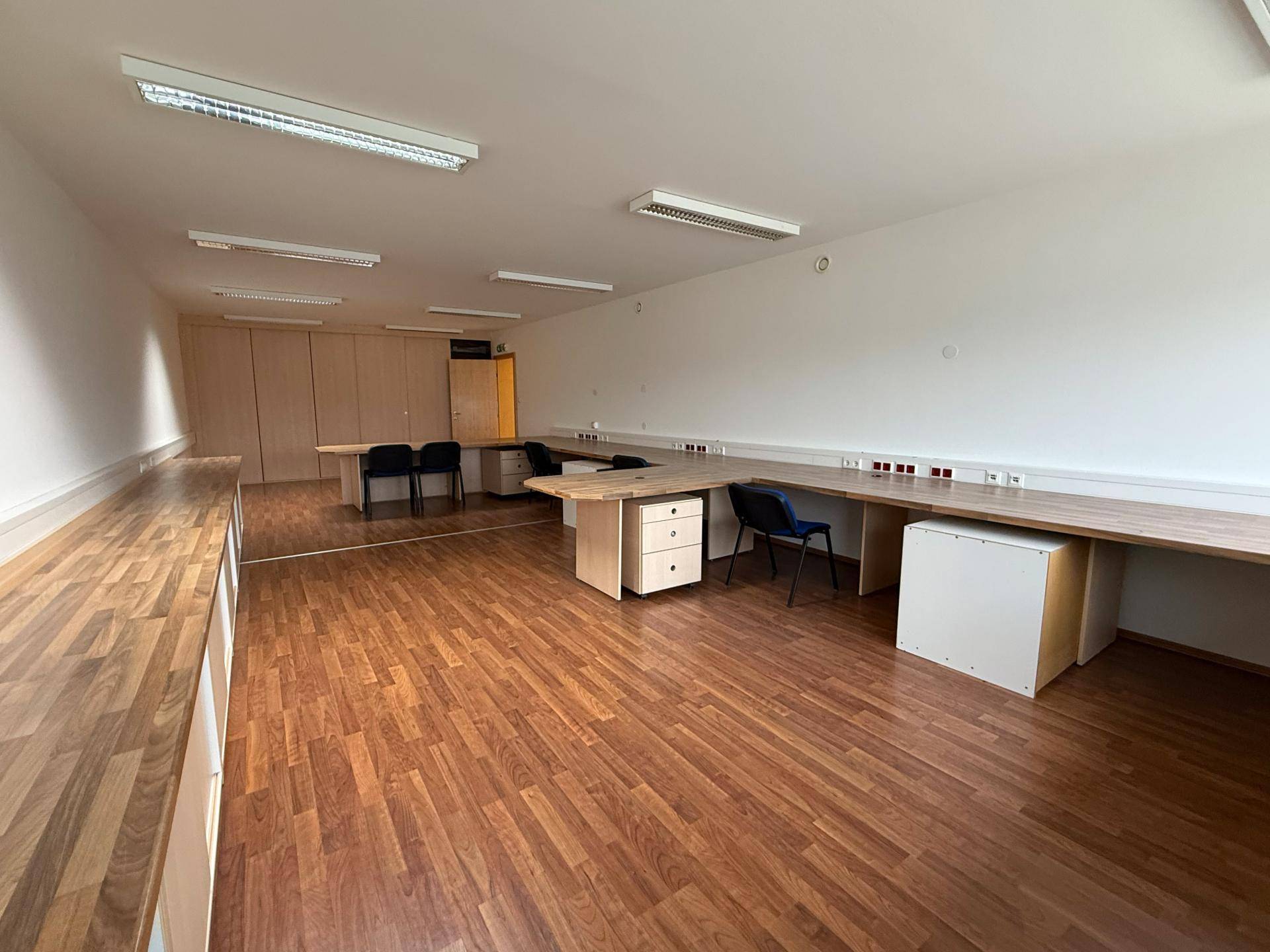 Helles Büro mit langen Arbeitsflächen und Schränken, bietet flexible Arbeitsplatzlösungen und Stauraum.