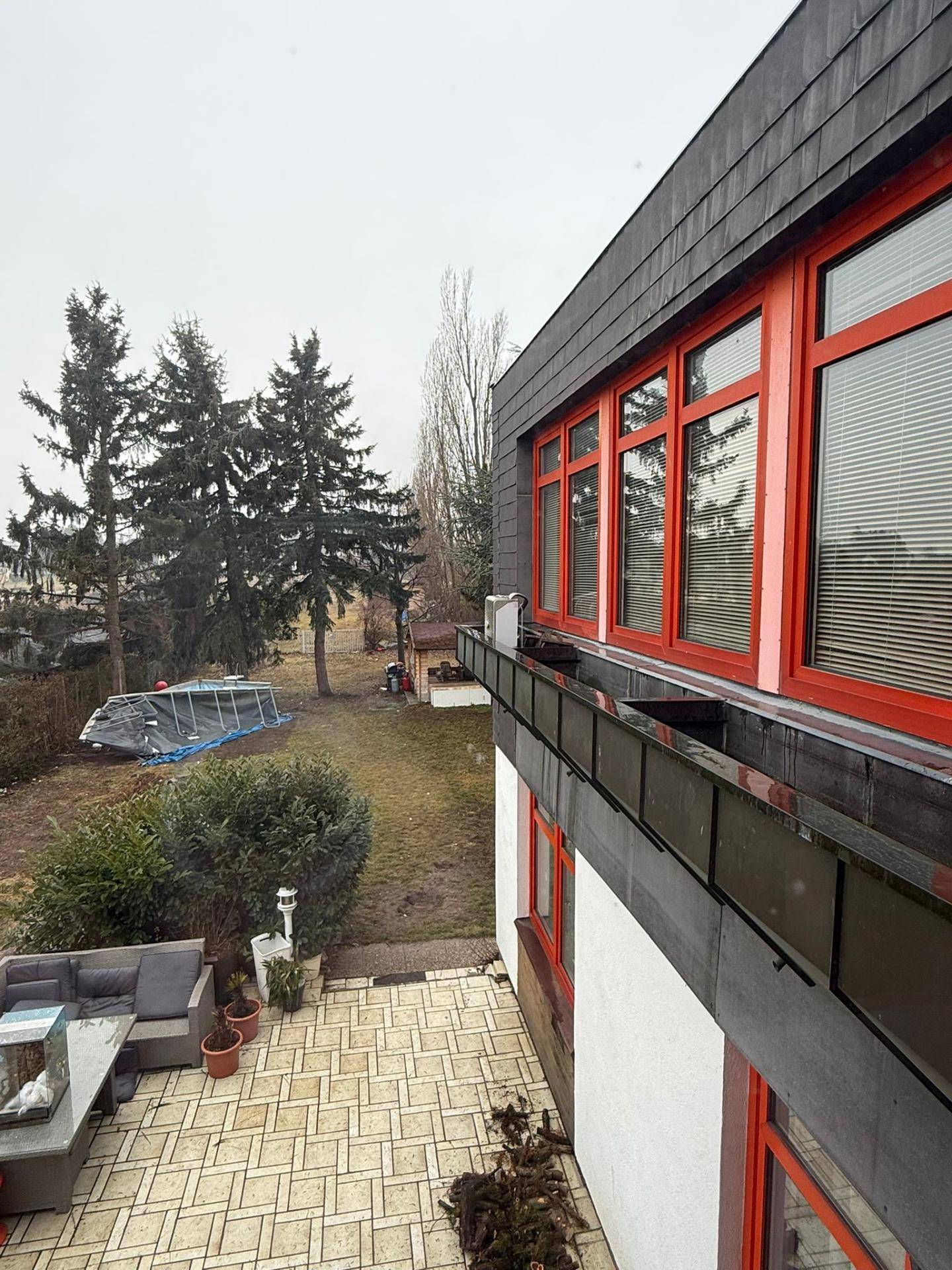 Blick von der Terrasse auf den Garten mit Outdoor-Sitzgruppe und einem aufgestellten Pool.