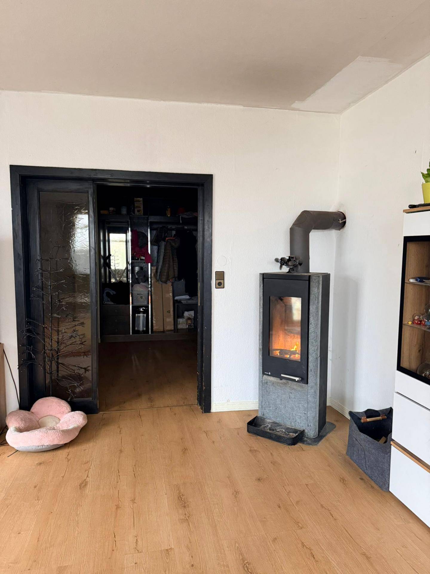 Wohnzimmer mit Laminatboden und einem modernen Holzofen, der Wärme spendet.
