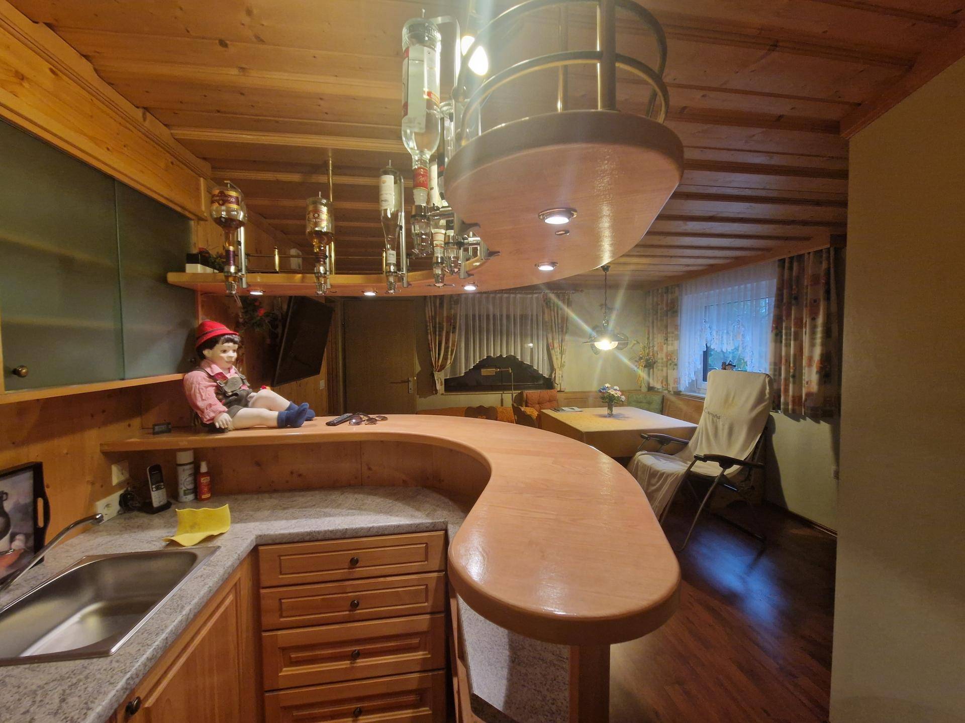 Gemütliche Bar mit Holztheke, integrierten Flaschenhaltern und Sitzbereich.