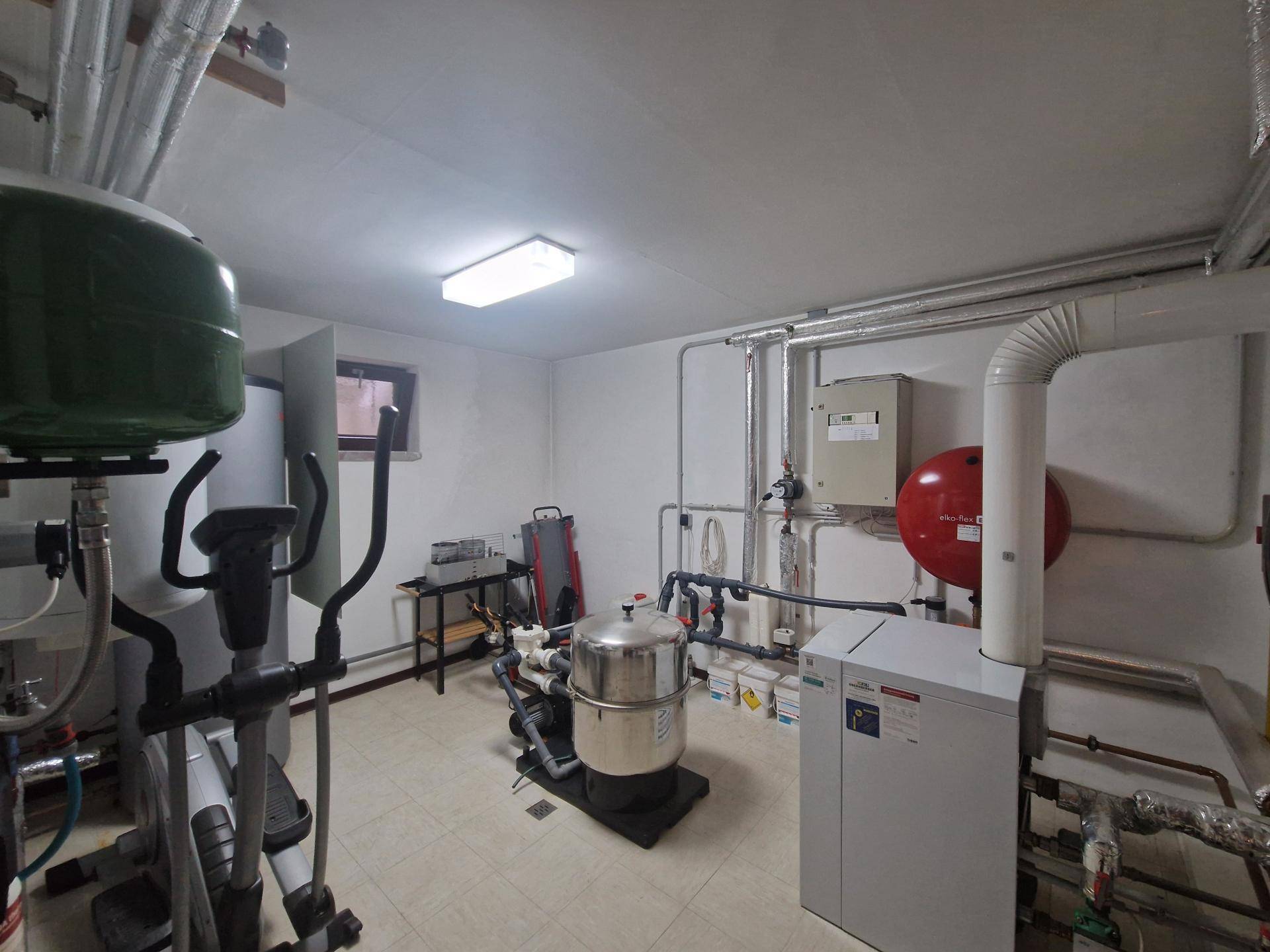 Heizungsraum mit moderner Anlage, Warmwasserspeicher und Fitnessgerät.