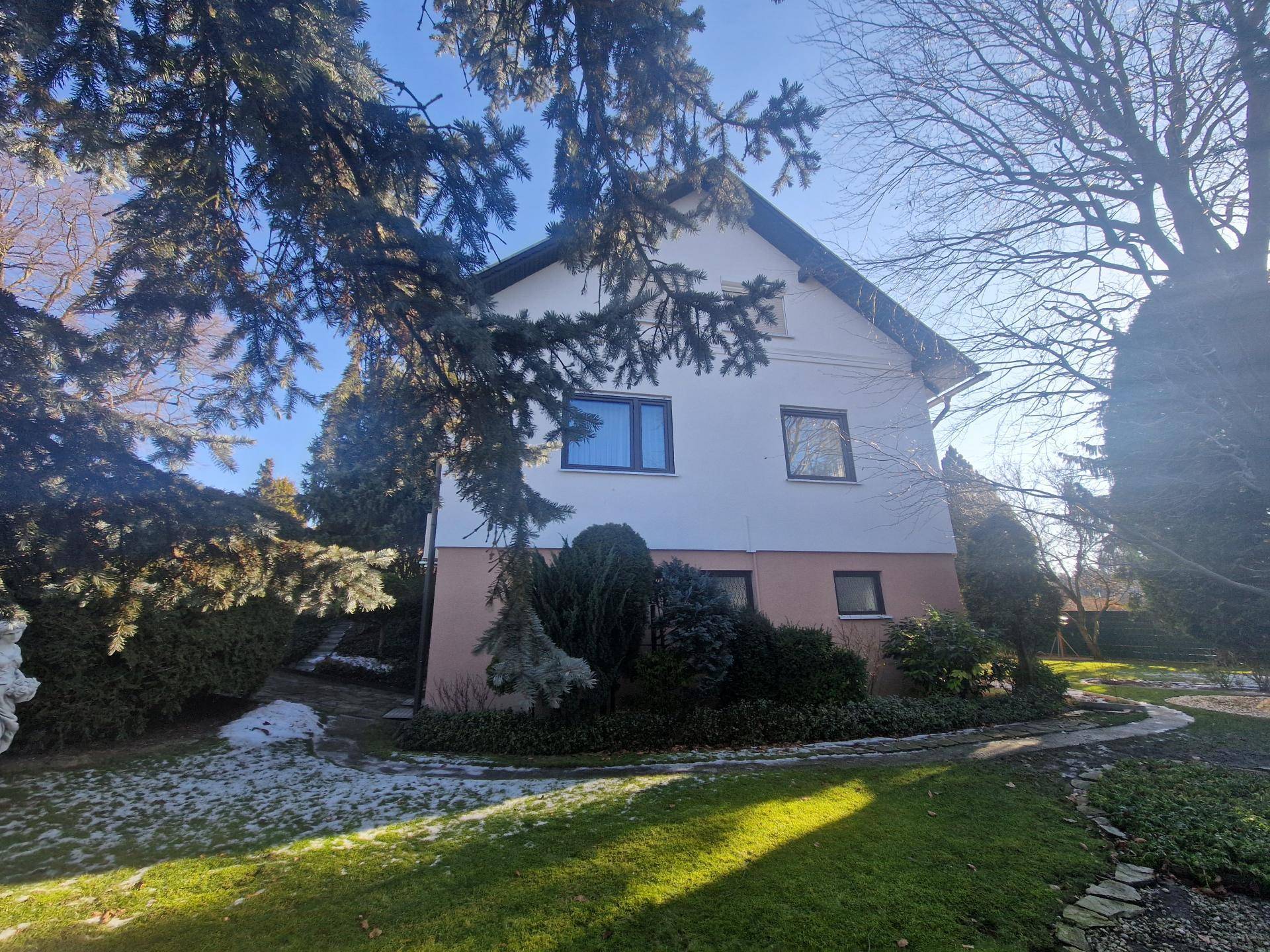 Rückansicht des Hauses mit großem Garten, Bäumen und Sträuchern im Winter.