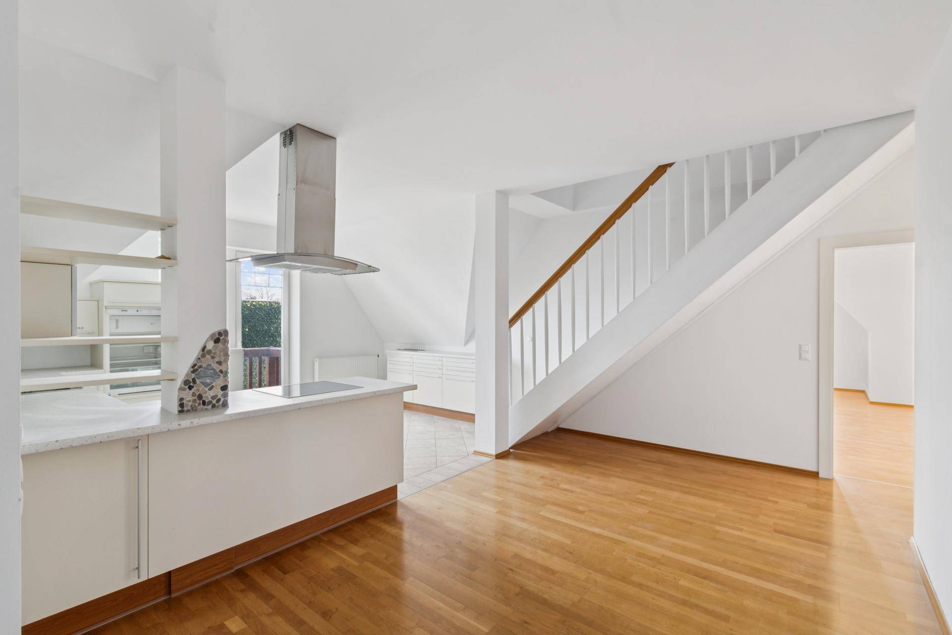 Kleine Küche mit Kochinsel, Dunstabzugshaube und Treppe zum oberen Stockwerk.