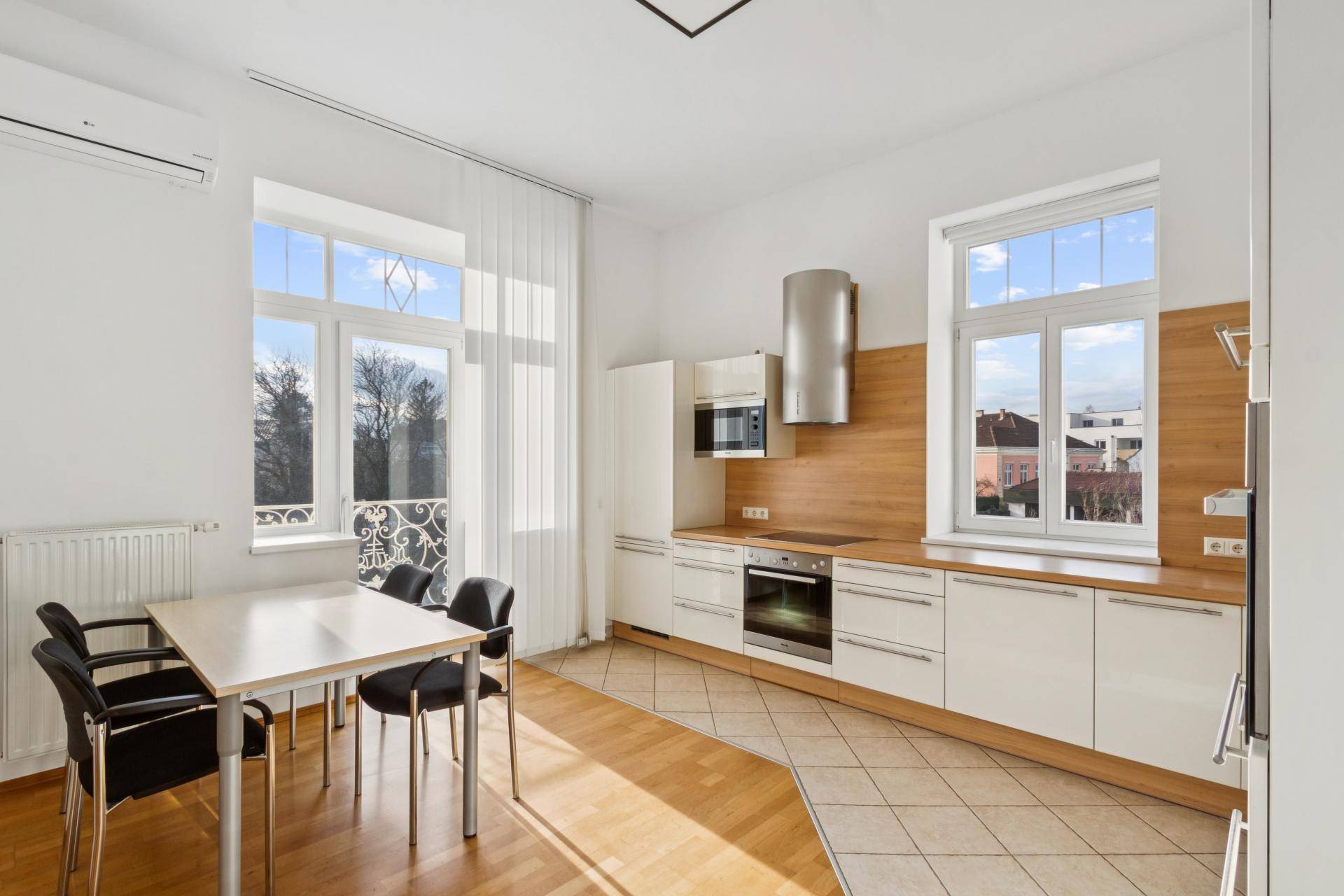 Helle Wohnküche mit Essbereich, modernen Geräten und Zugang zu einem Balkon.