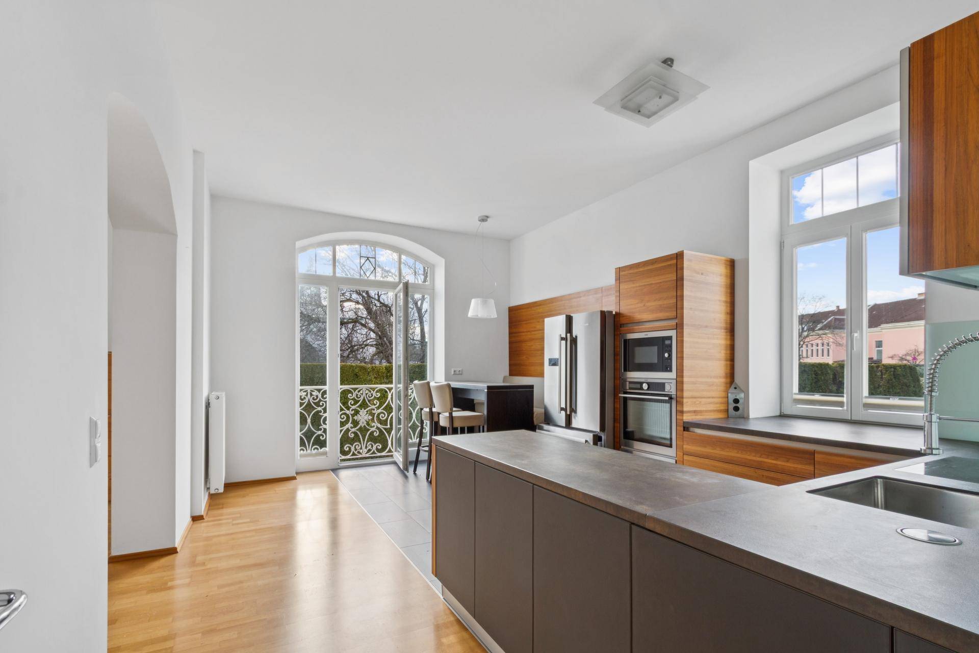 Moderne Küche mit Holzelementen, integrierten Geräten und Zugang zu einem französischen Balkon.