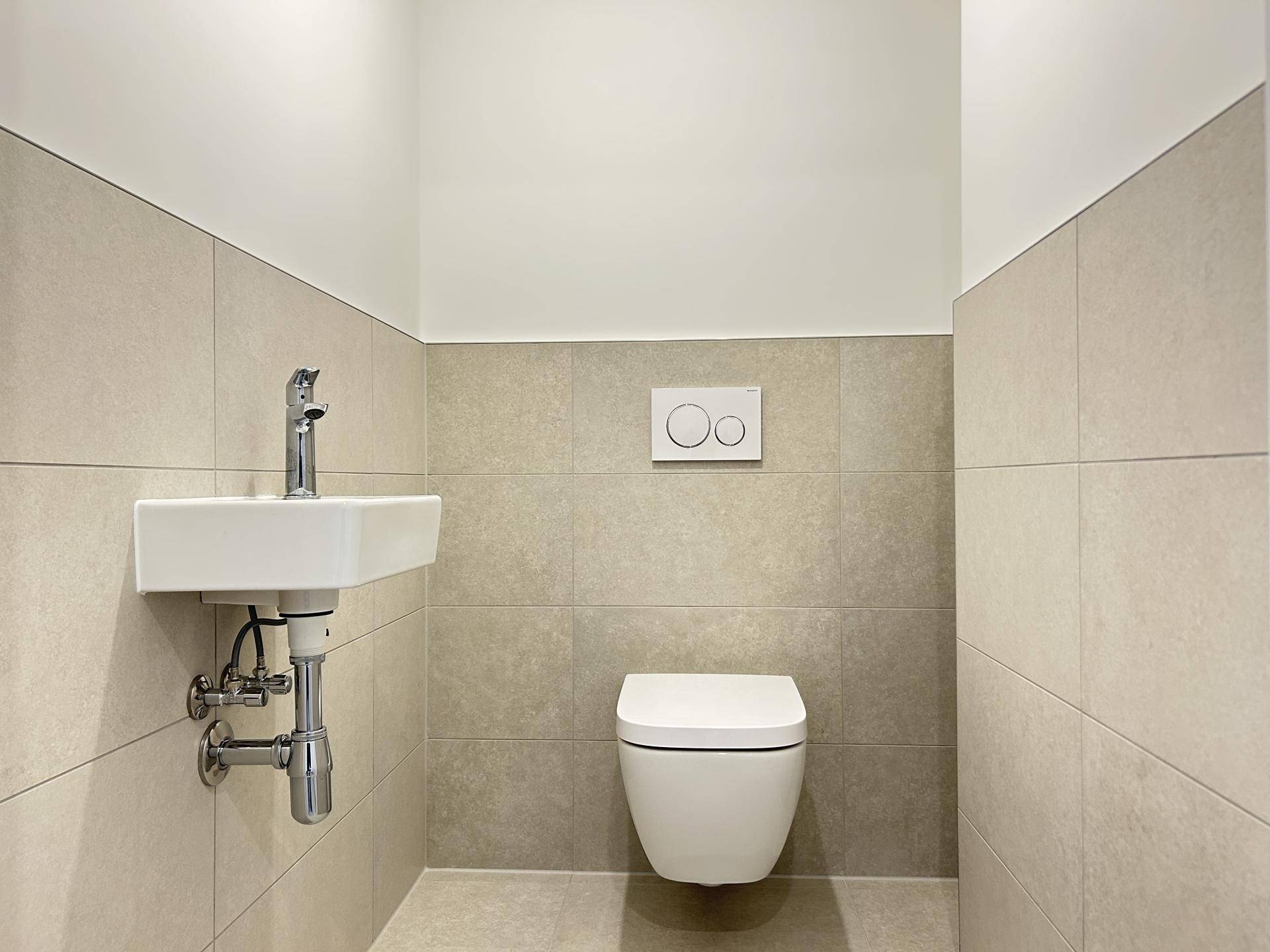 Modernes Gäste-WC mit wandhängender Toilette und kleinem Waschbecken.